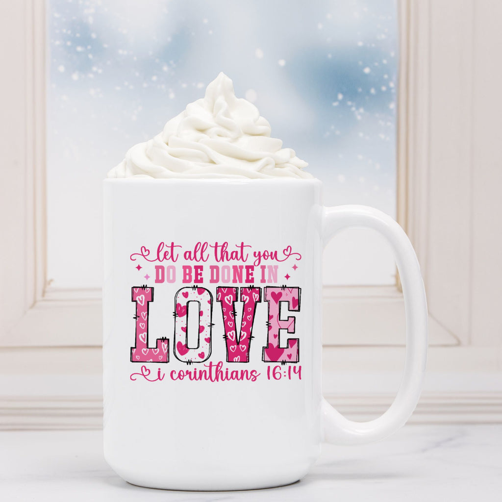 White mug with pink text and design, filled with hot chocolate and whipped cream, against a snowy window background.