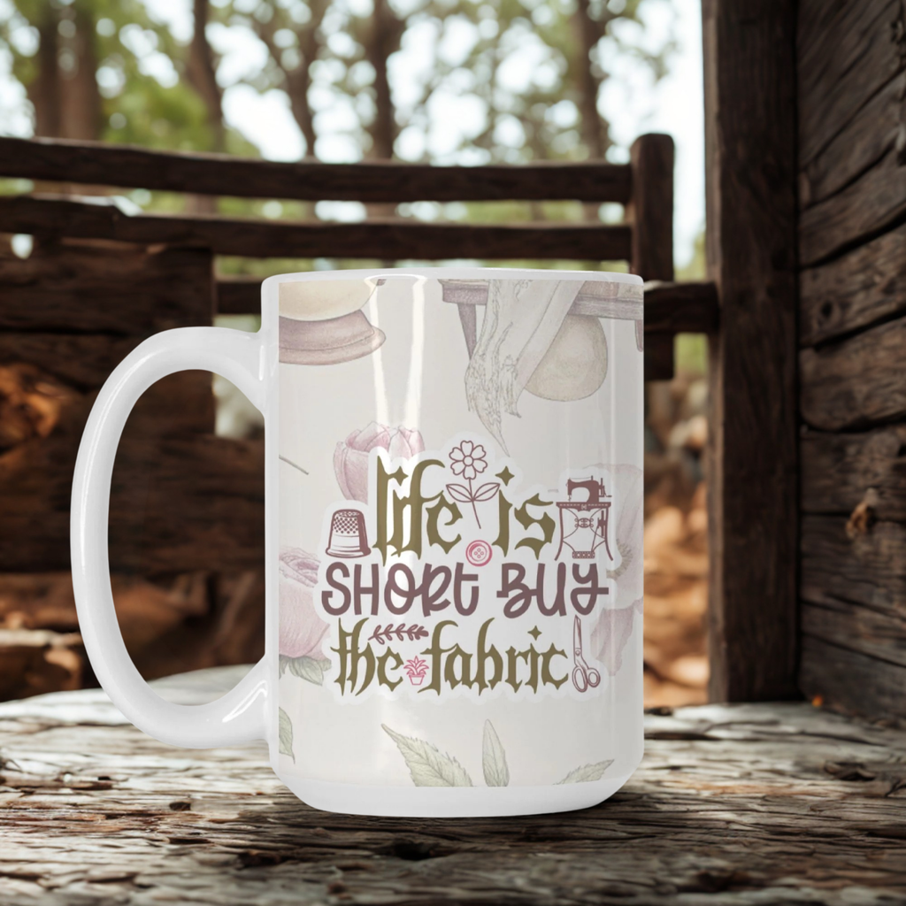 Mug with 'Life is short, buy the fabric' design on a wooden surface with blurred background