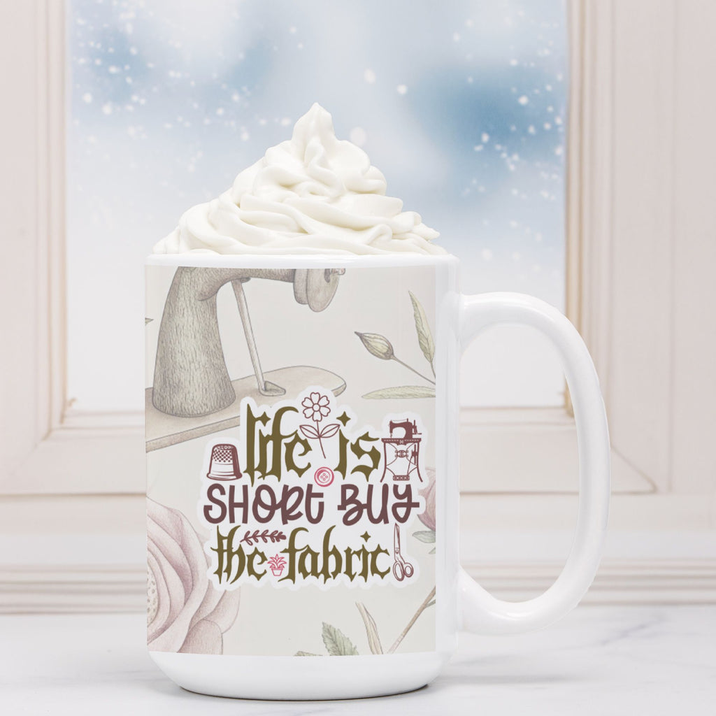 White mug with fabric-themed design and text 'Life is short, buy the fabric' filled with hot chocolate and whipped cream.