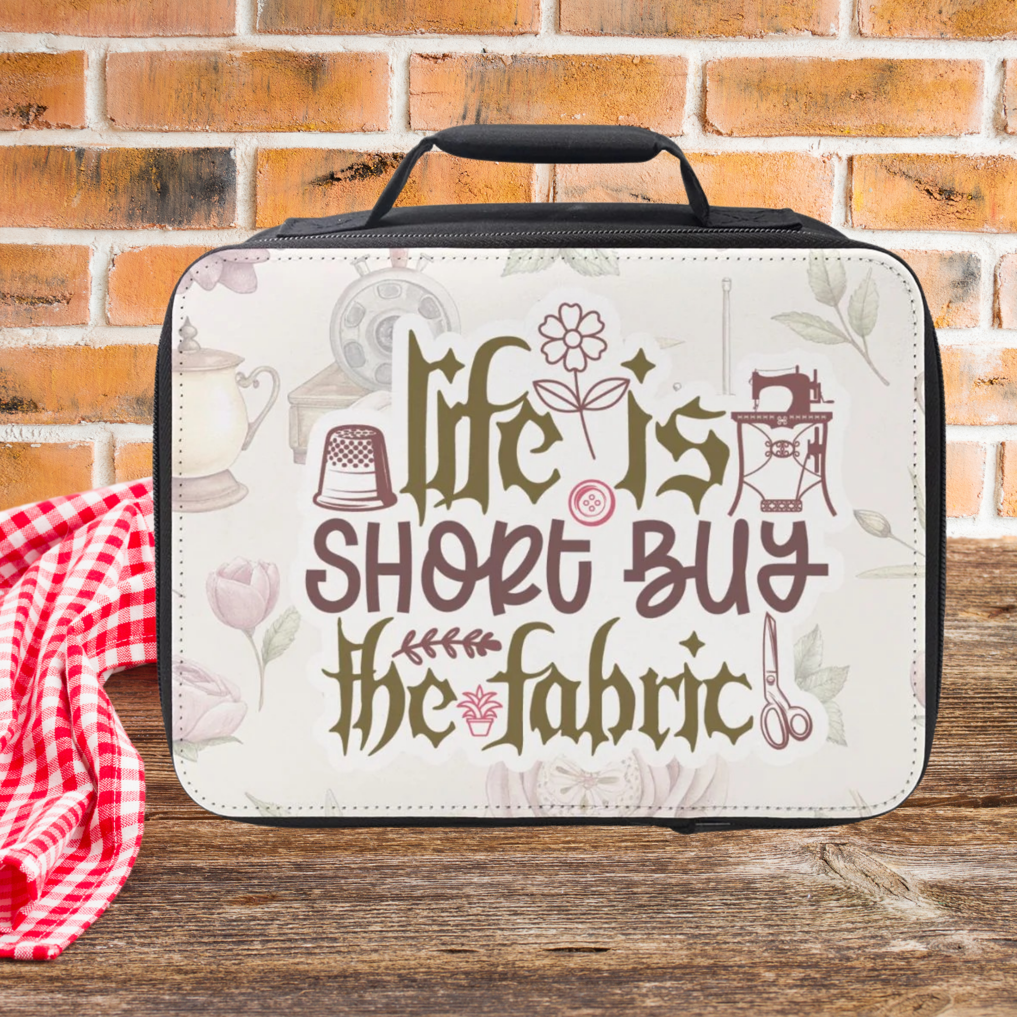 insulated lunch bag with 'Life is short, buy the fabric' text on a wooden picnic table against a brick wall background