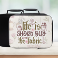 Insulated lunch box with sewing-themed design and text on a blurred background