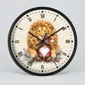 Round wall clock with a black frame and Roman numeral hour markers, featuring an illustration of a golden lion and a small gnome on the clock face, shown against a light gray background.