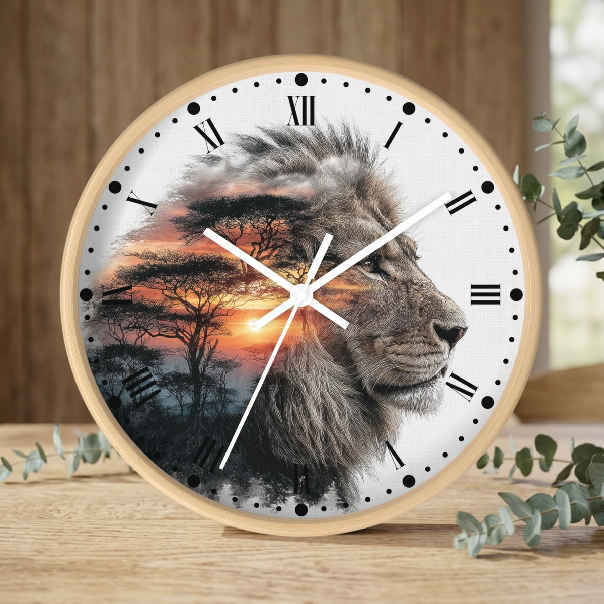 A round wall clock with a light wood frame sits on a wooden tabletop. The clock face features a photographic lion head in profile overlaid with a double-exposure African savanna landscape at sunset.