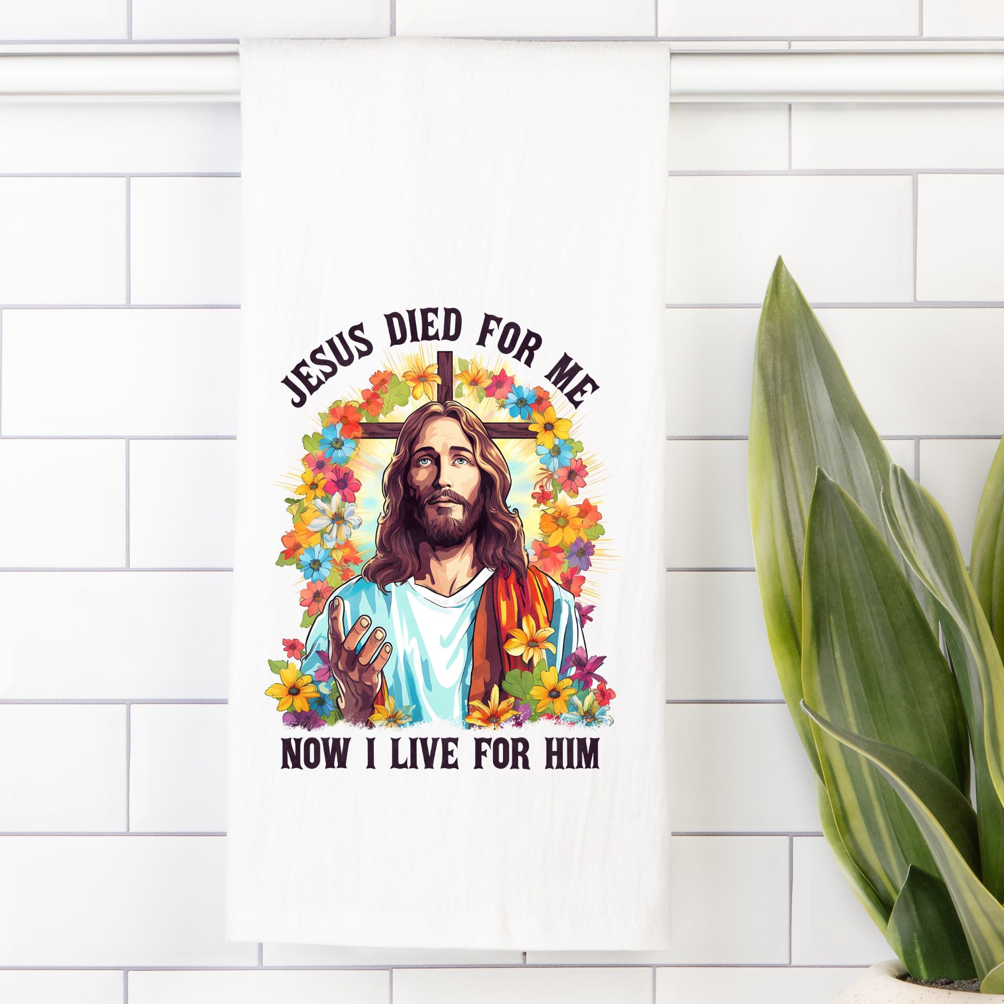 Tea towel with a colorful design of Jesus on a white tiled wall with a plant.