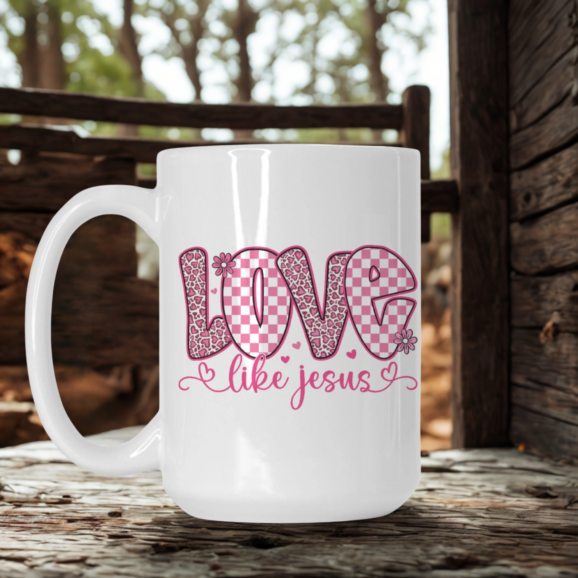 White mug with pink 'Love like Jesus' design on a wooden surface