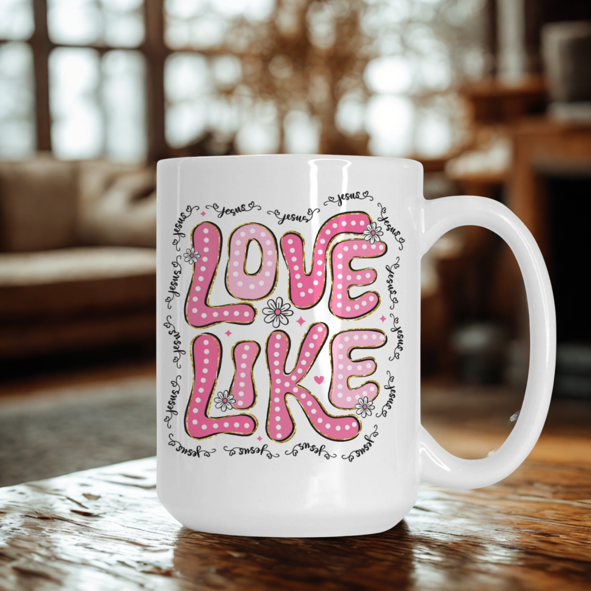 White mug with pink and black text 'LOVE LIKE' on a wooden surface with a blurred background