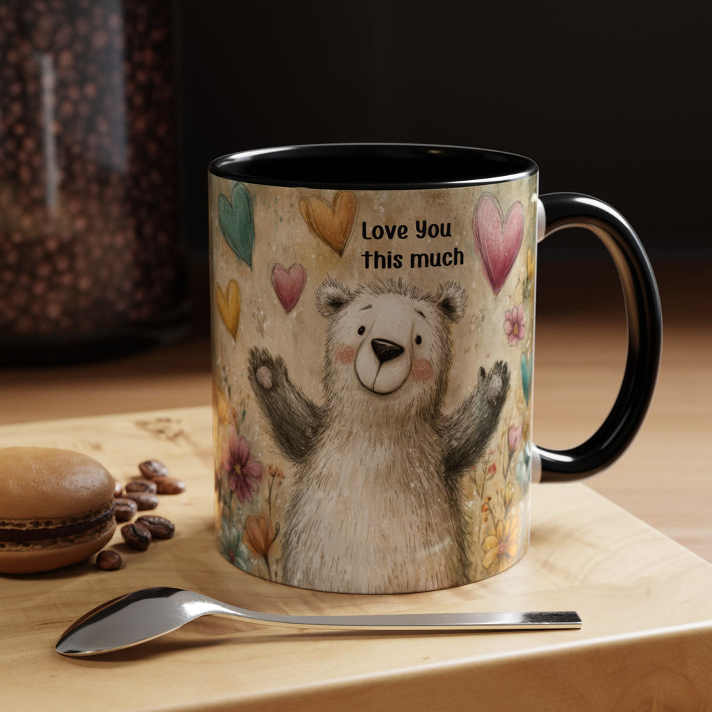 11oz. black accent mug with a bear illustration and 'Love You this much' text on a wooden surface with coffee beans and a macaron.
