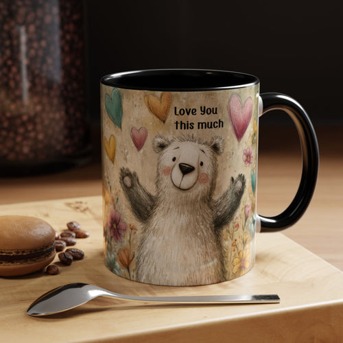 11oz. black accent mug with a bear illustration and 'Love You this much' text on a wooden surface with coffee beans and a macaron.