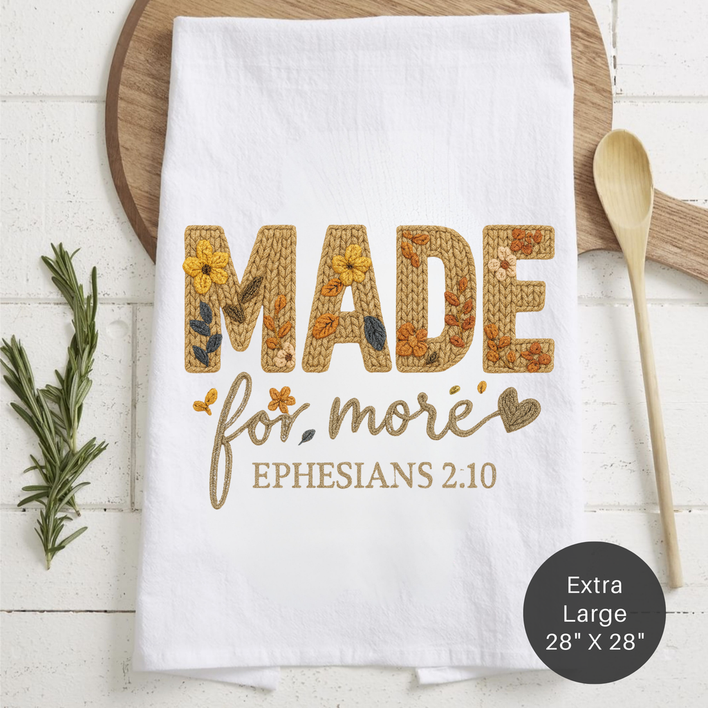 White towel with embroidered text and design on a wooden surface