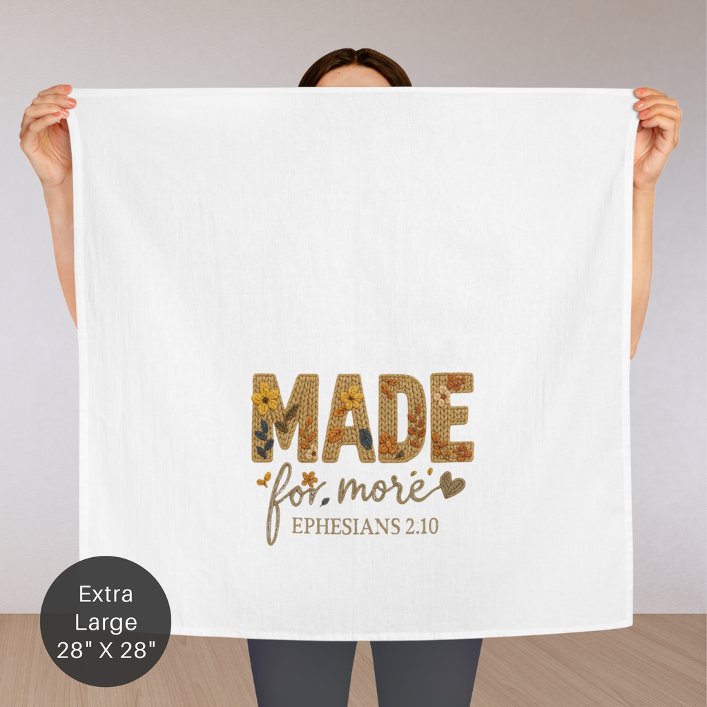 Person holding an extra large white tea towel with 'Made for more' text and Bible verse on a neutral background