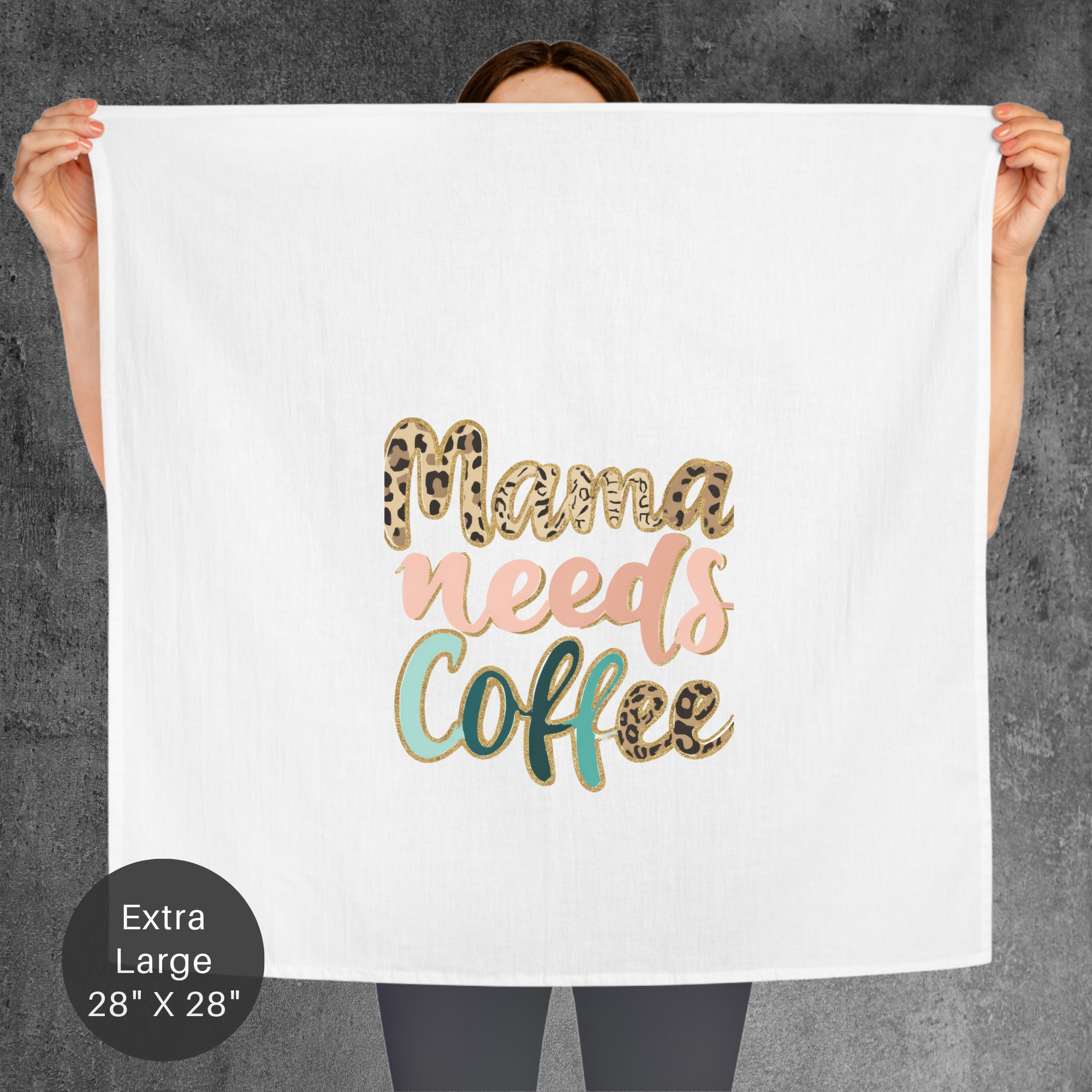 Person holding a towel with 'Mama needs coffee' text in gold, pink, and green on a gray background