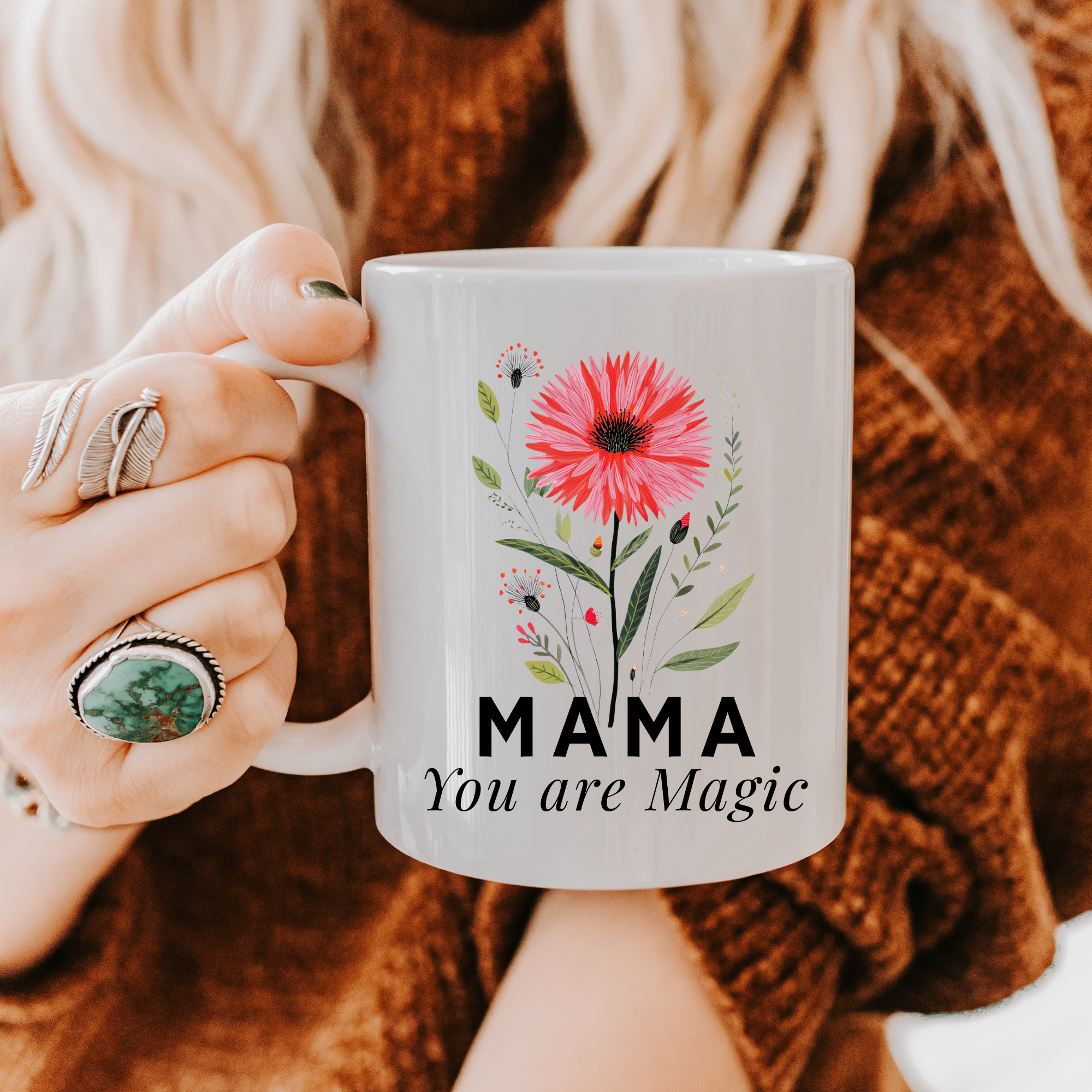 Person holding an 11oz mug with floral design and 'MAMA You are Magic' text, wearing a brown sweater.