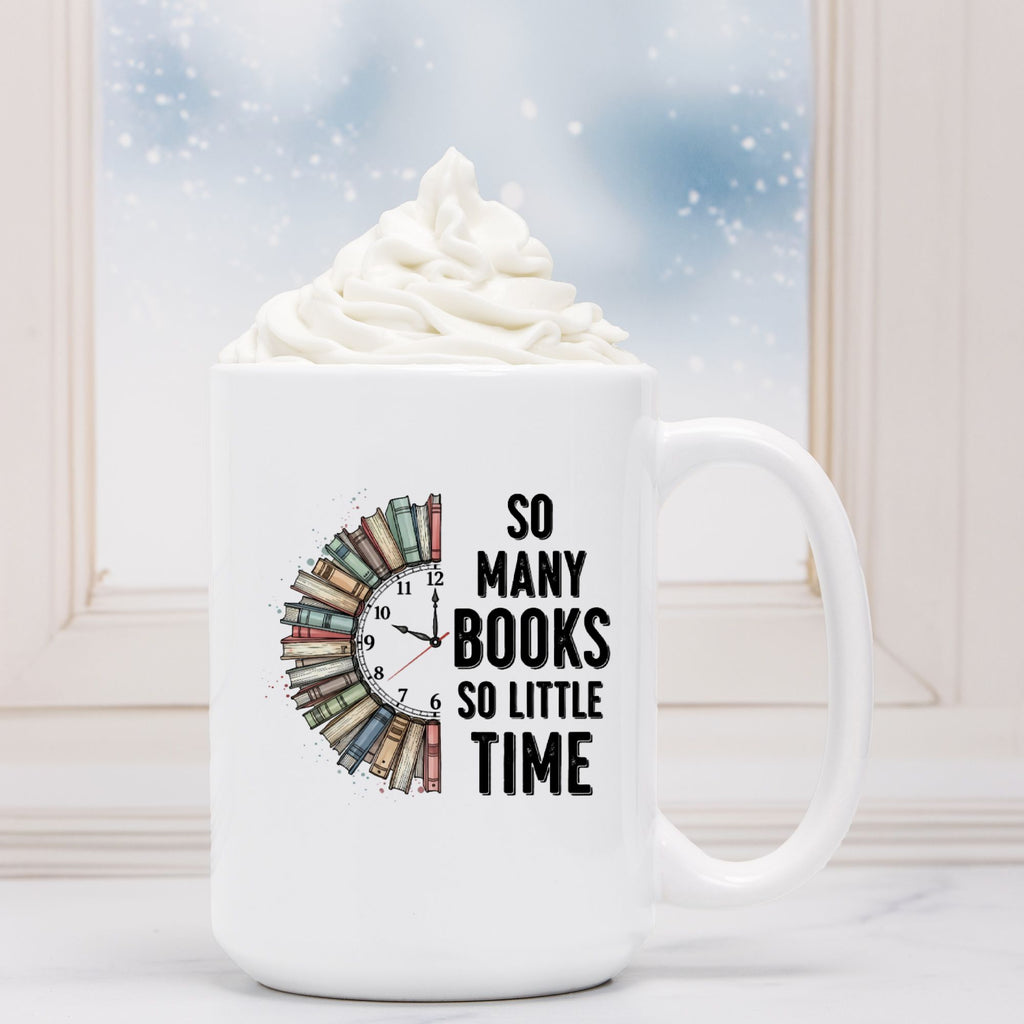 White mug with book-themed design and text 'So Many Books So Little Time' in front of a hot chocolate with whipped cream.