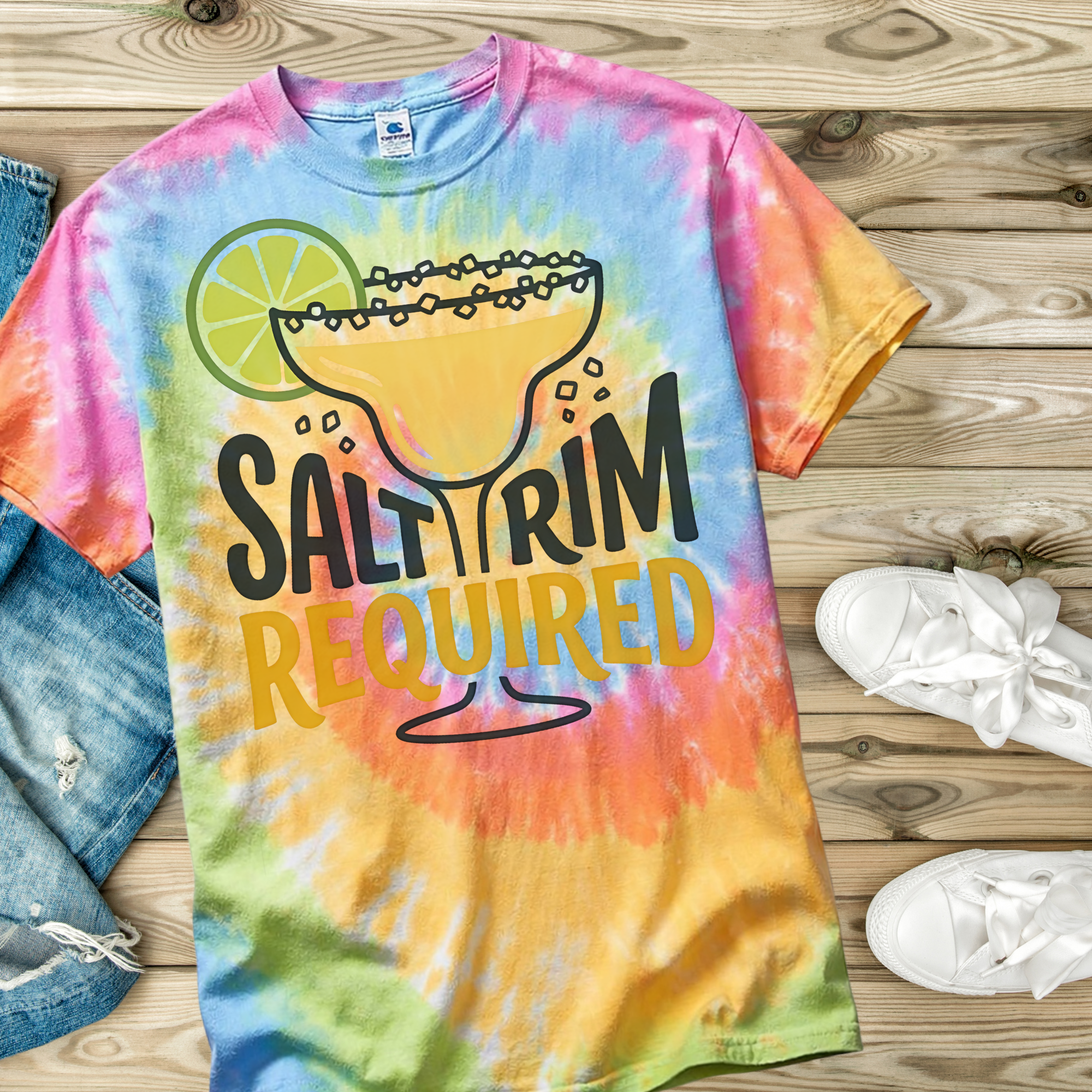Colorful tie-dye t-shirt with a margarita graphic and 'Salt Rim Required' text on a wooden surface.