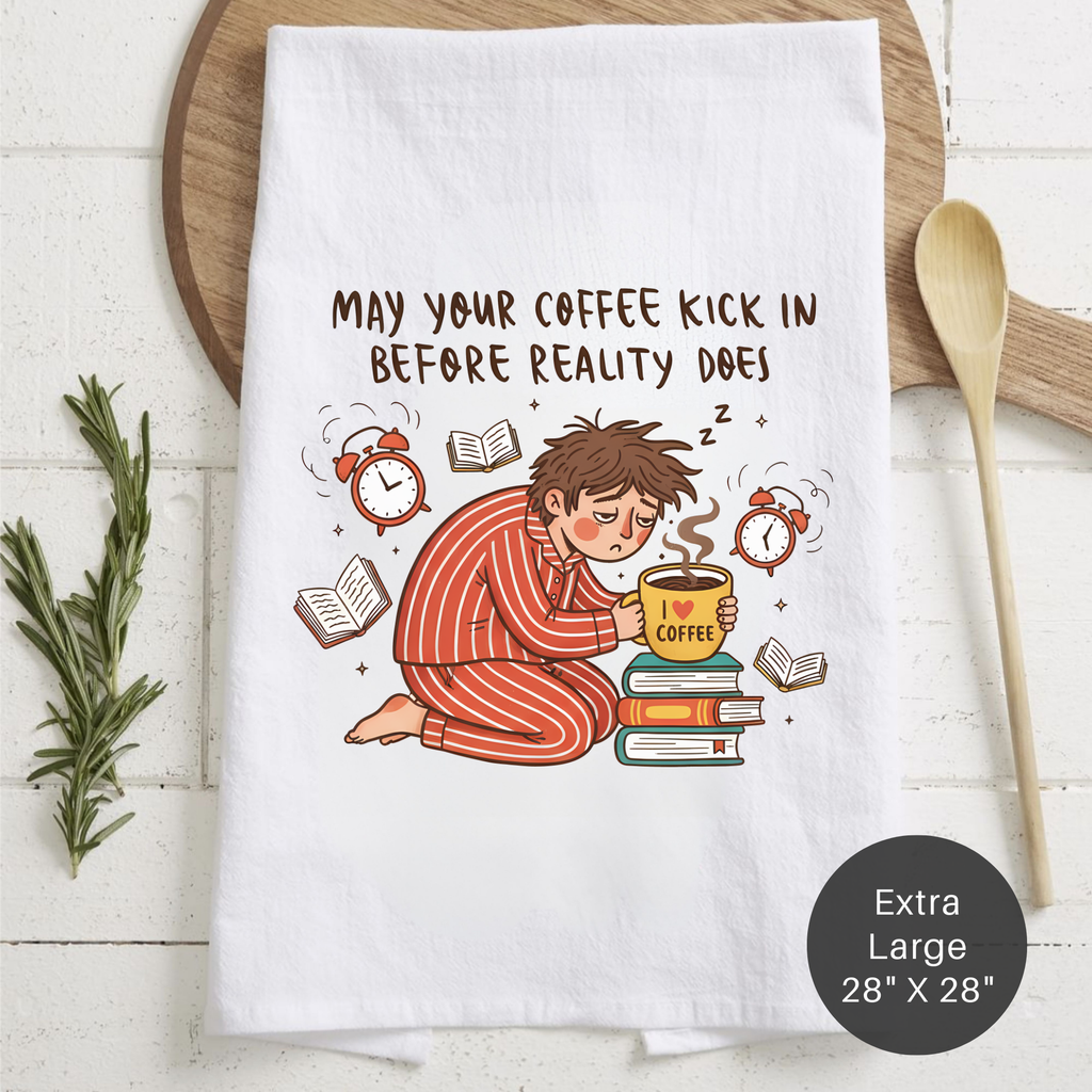 Tea towel with a cartoon character and text 'May Your Coffee Kick In Before Reality Does' on a wooden surface