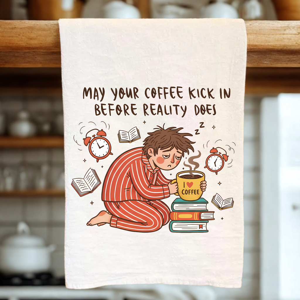 Towel with a cartoon character holding a coffee cup and text 'May your coffee kick in before reality does' in a kitchen setting.