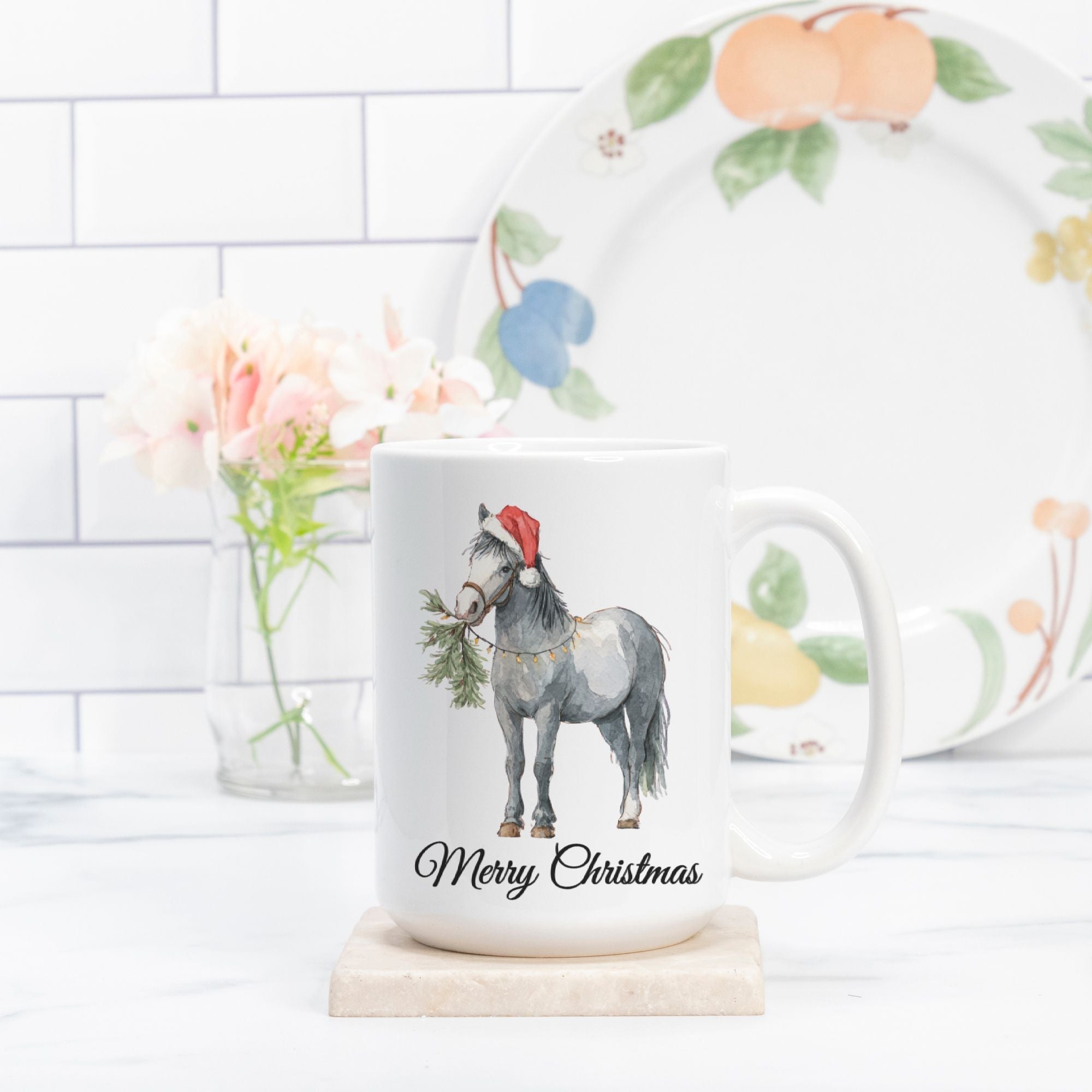 Mug with a horse illustration wearing a Santa hat and 'Merry Christmas' text, placed on a surface with a decorative plate in the background.