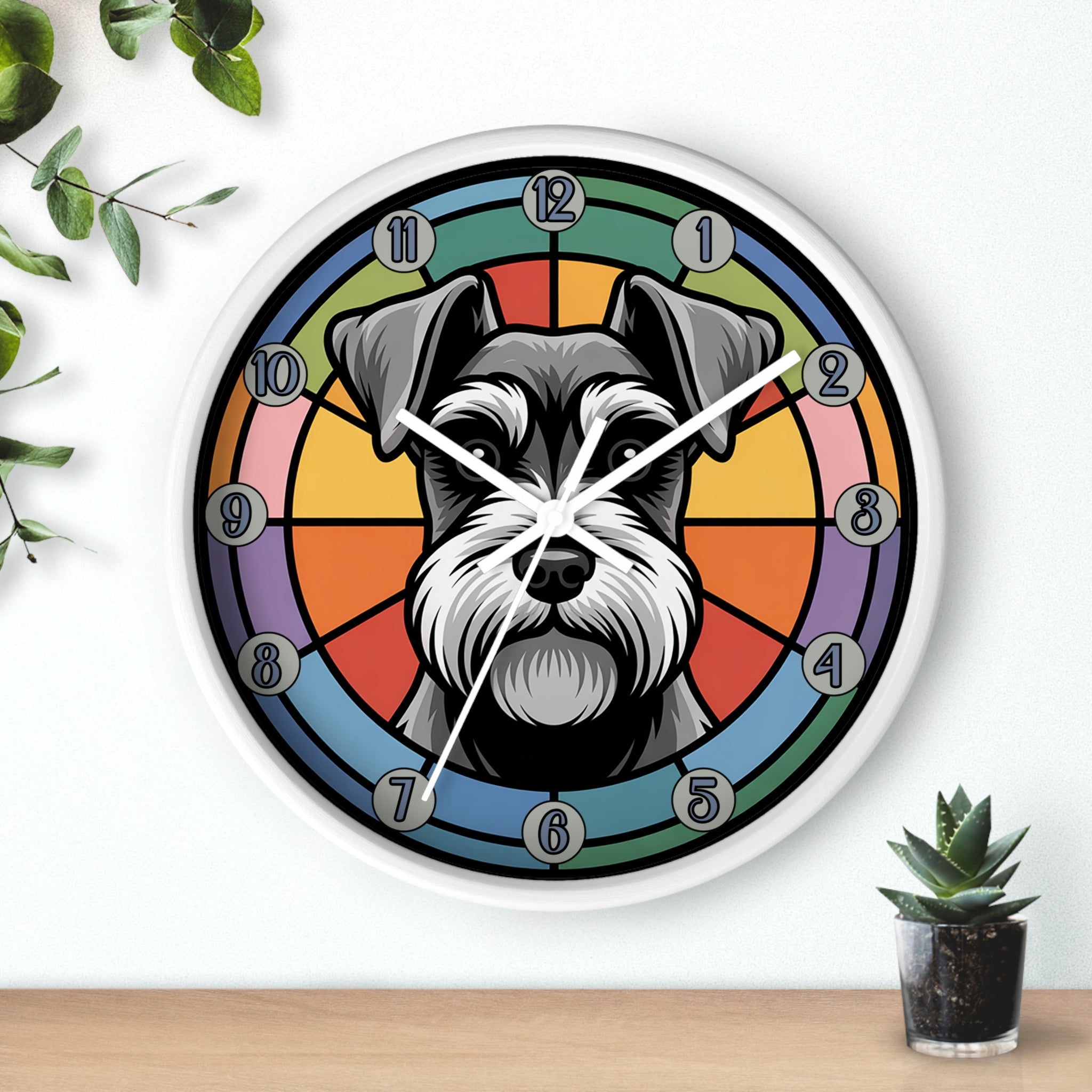 Wall clock with a schnauzer dog design on a colorful background, placed on a wooden surface with plants.