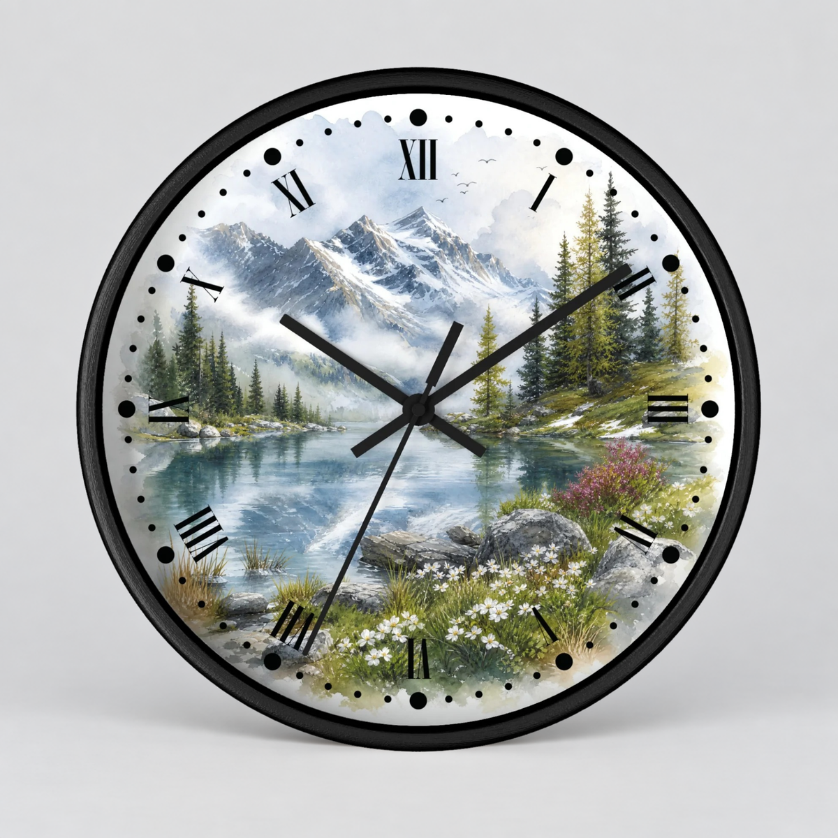 A round wall clock with a black frame and a scenic landscape print featuring mountains, a lake, pine trees, and wildflowers. The clock face has black Roman numerals and black hands, photographed against a light gray background.