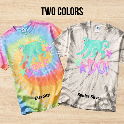 Two tie-dye t-shirts with a monkey graphic and text on a wooden surface.