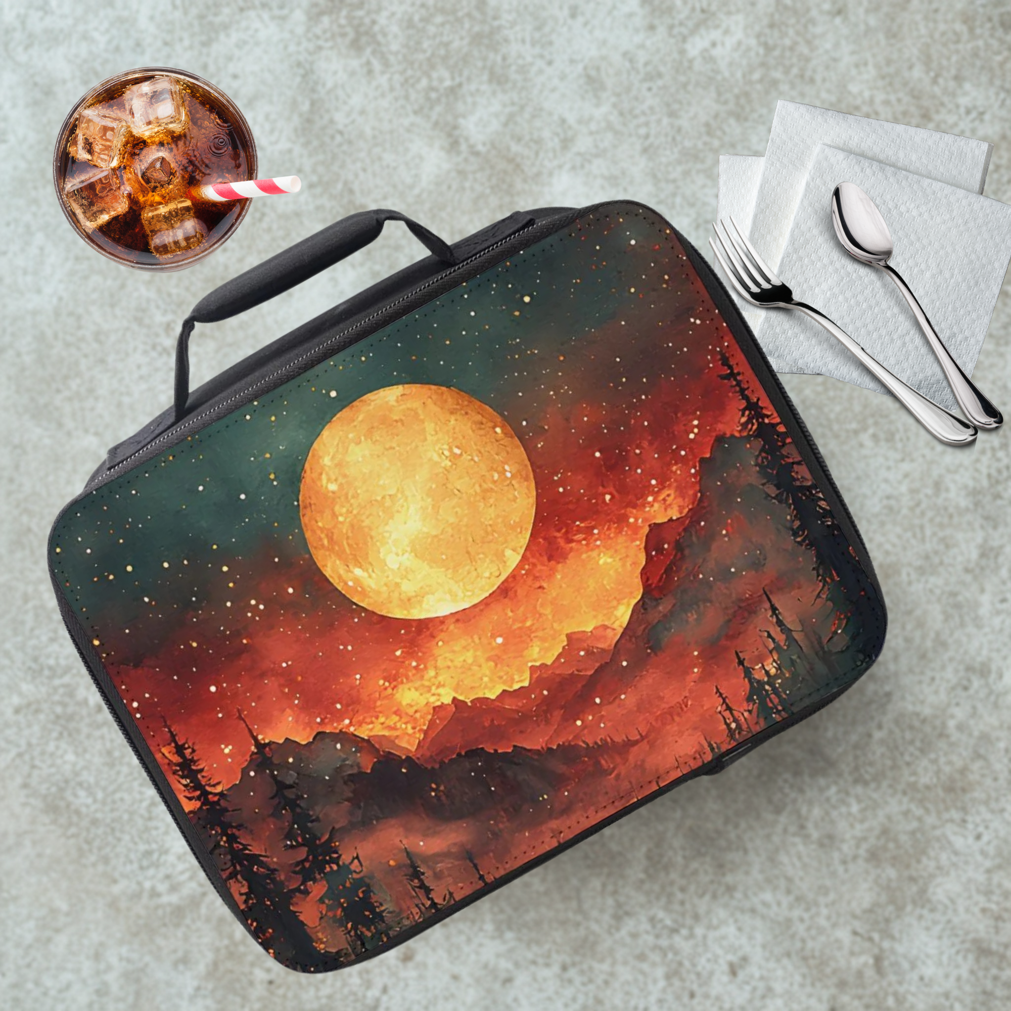  insulated lunch bag with a sunset design on a cafeteria table with a drink and utensils.