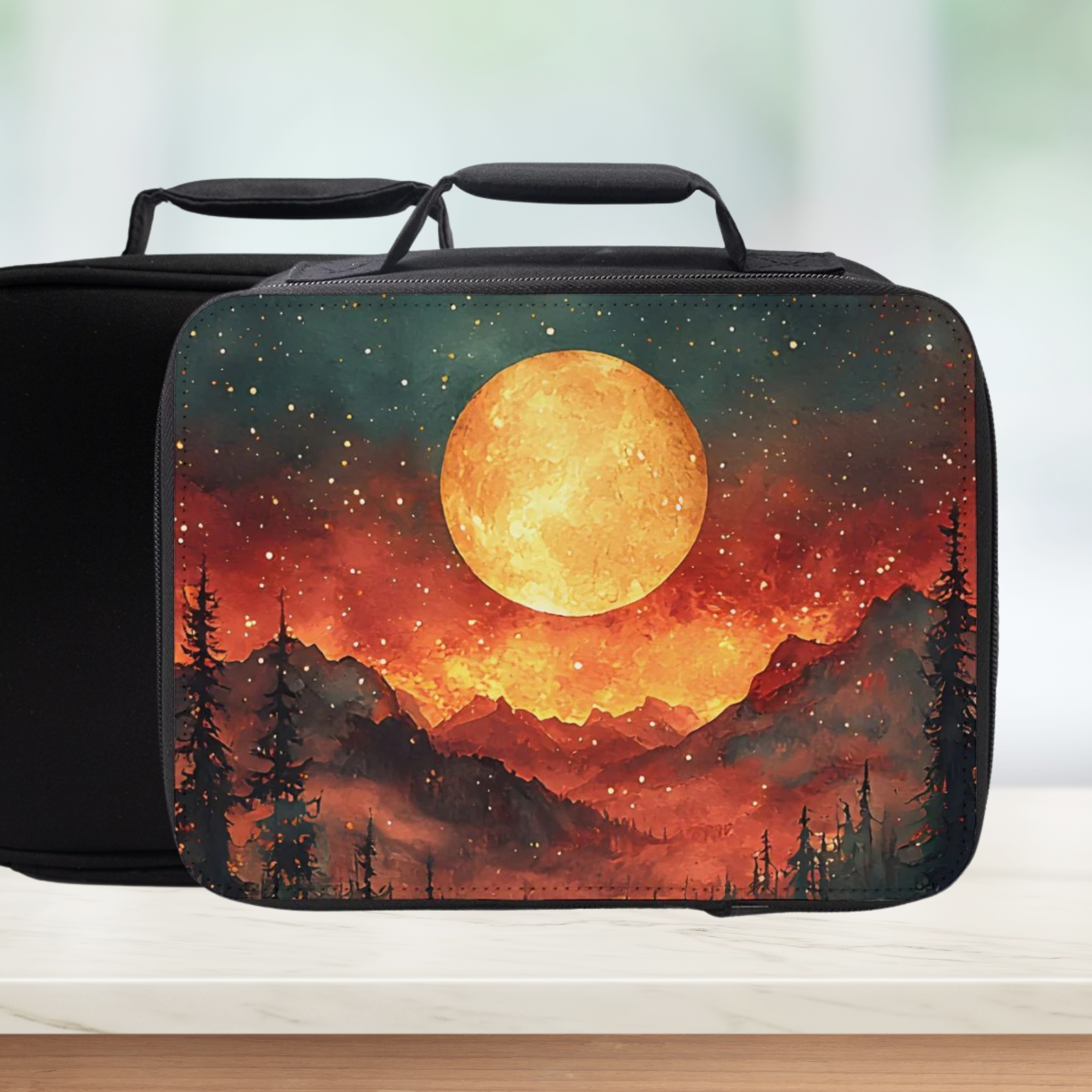 Black lunch bag with a sunset design featuring mountains and trees on a white surface.