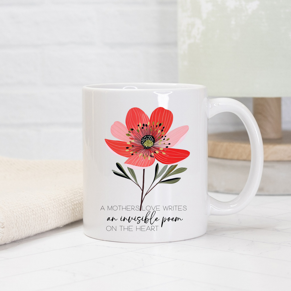 White mug with a red flower design and text on a light background