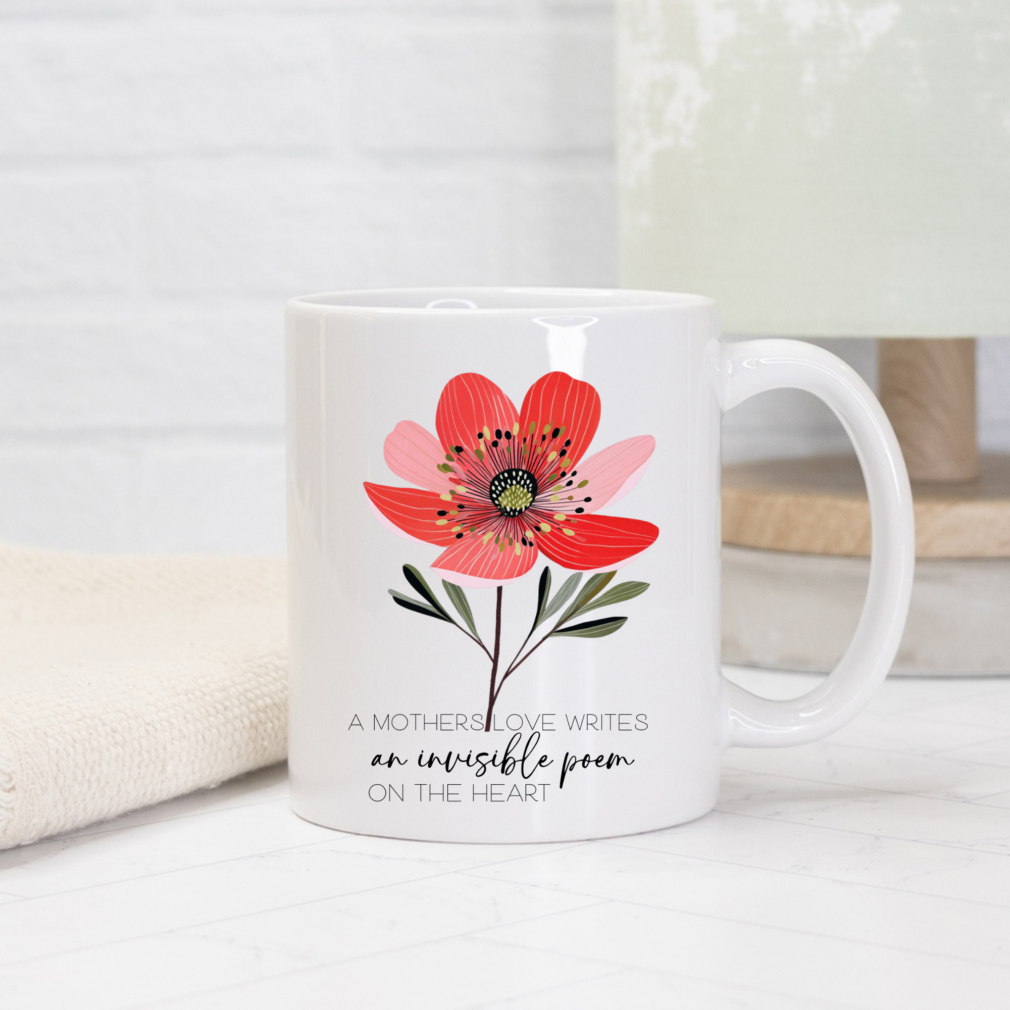 White mug with a red flower design and text on a light background