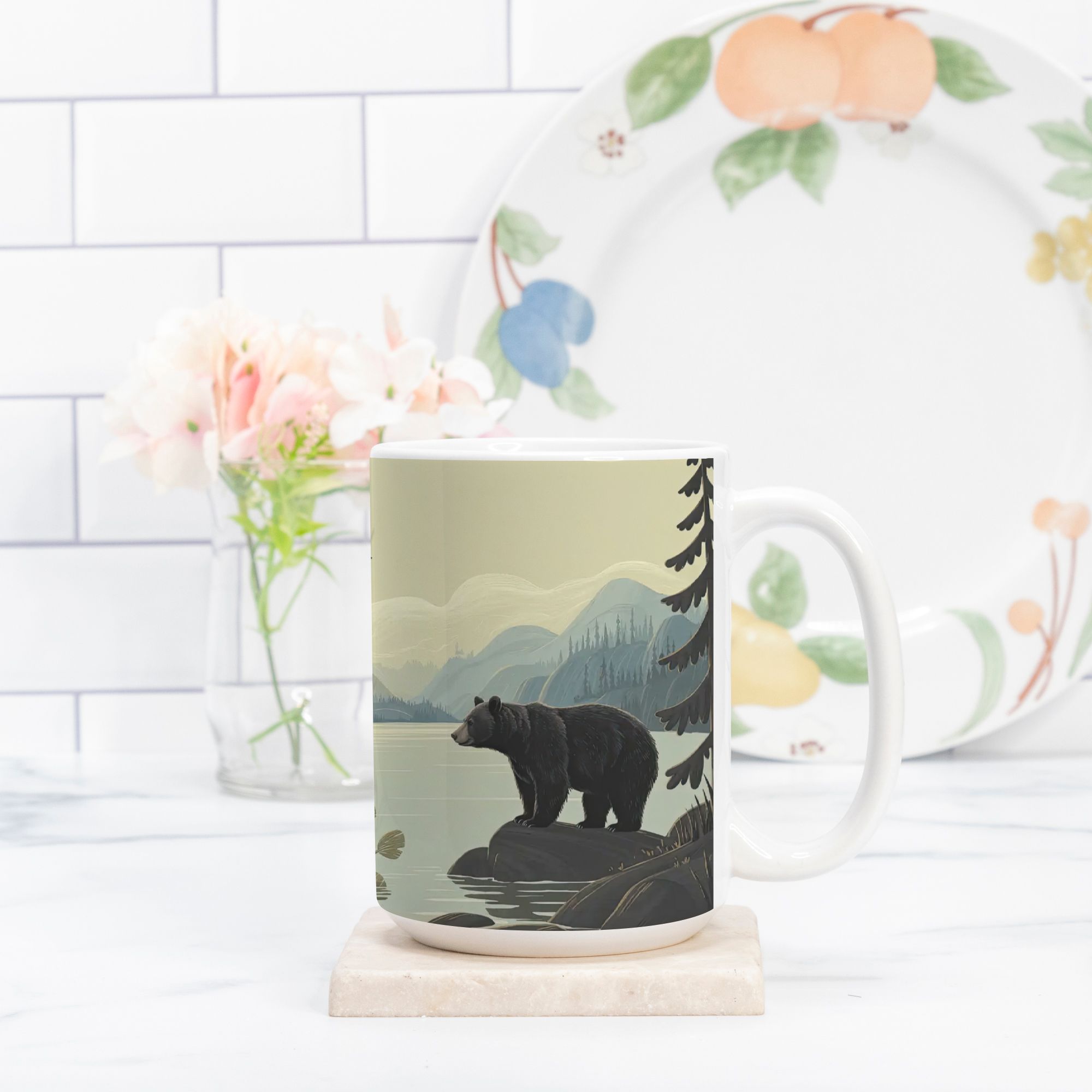 Mug with bear design on a marble coaster, next to a floral plate on a white tiled wall background.