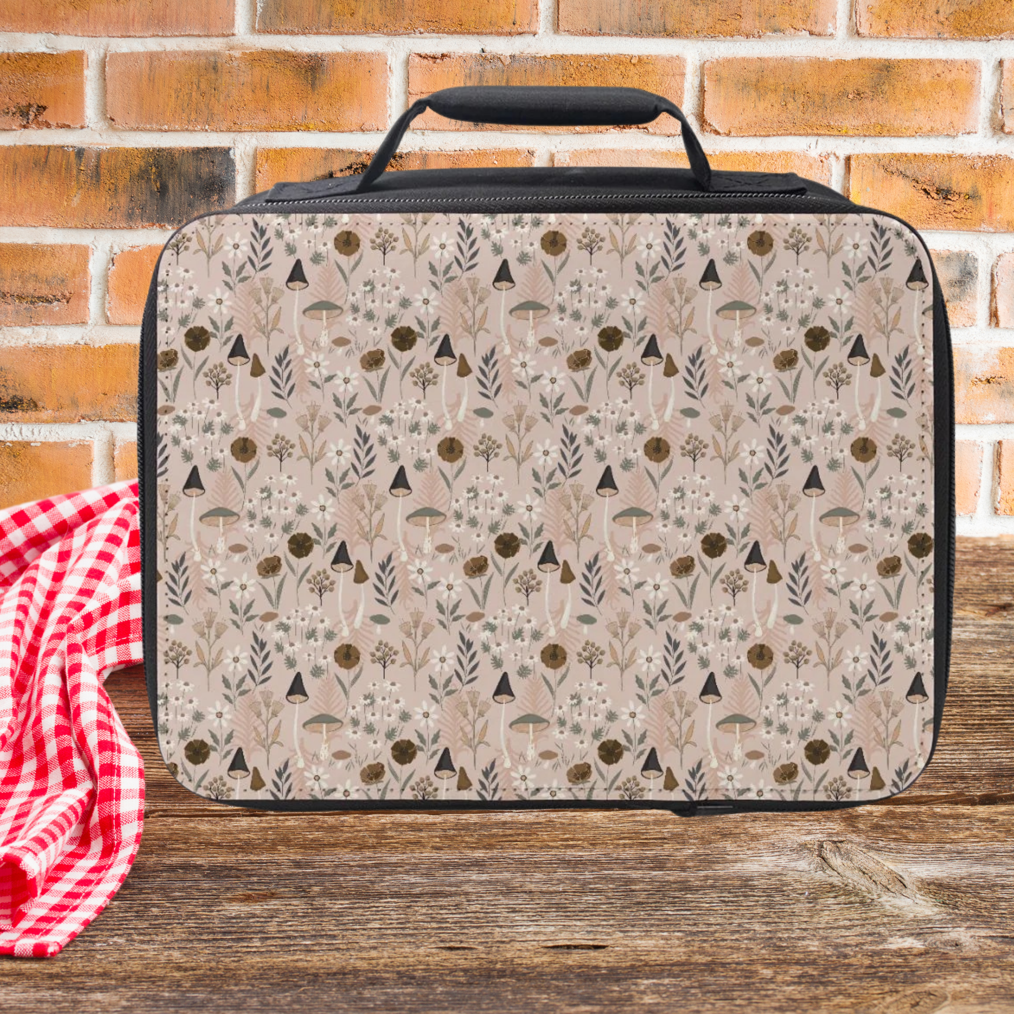 Insulated lunch bag with nature-themed pattern on a wooden picnic table and brick wall background