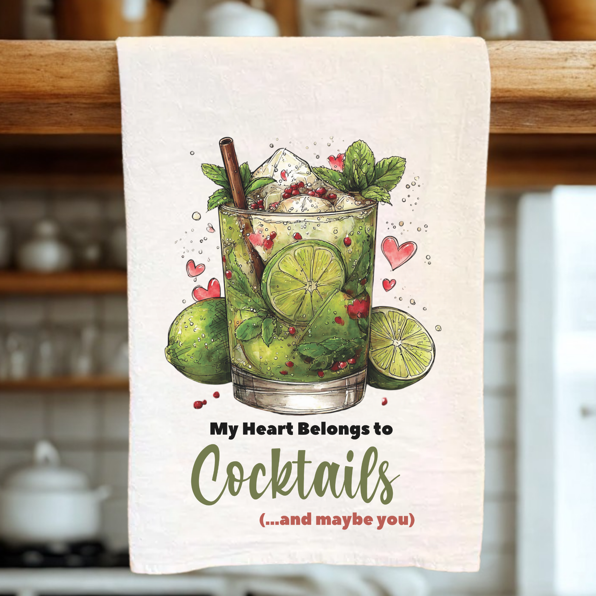 Tea towel with cocktail design and text hanging on a wooden rack.
