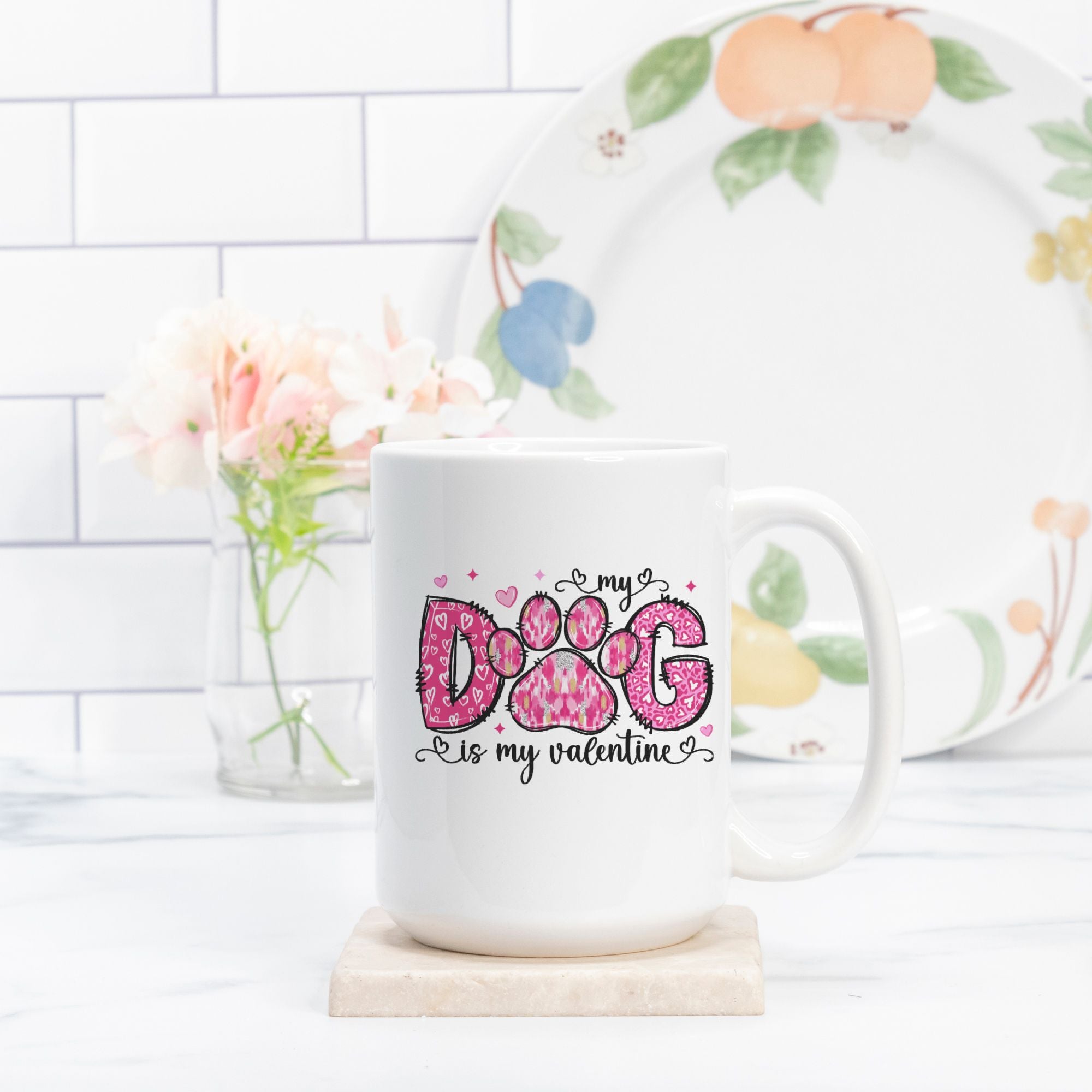 White mug with 'My dog is my valentine' design on a white surface with a floral plate in the background.