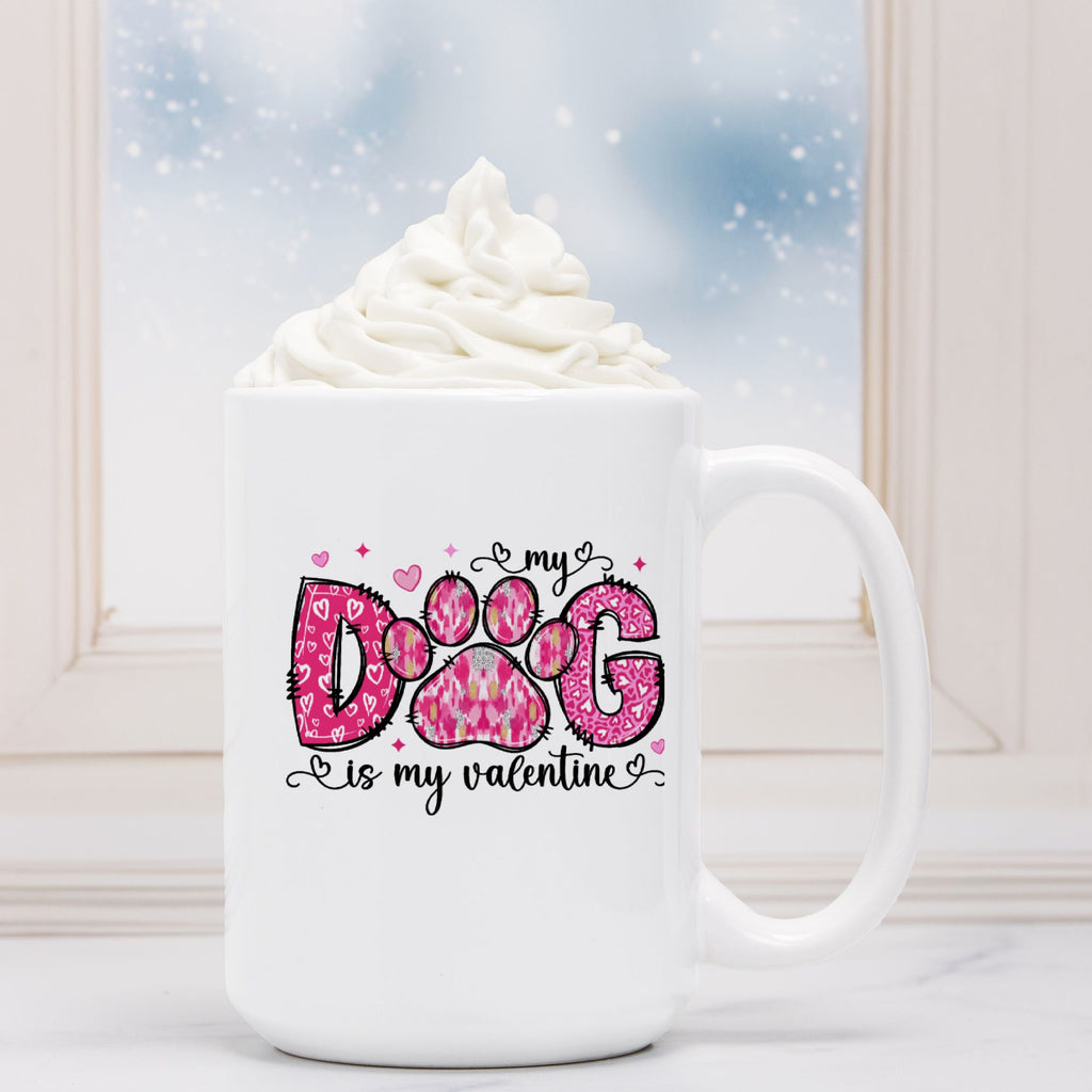 White mug with 'My dog is my valentine' design in front of a hot chocolate with whipped cream.
