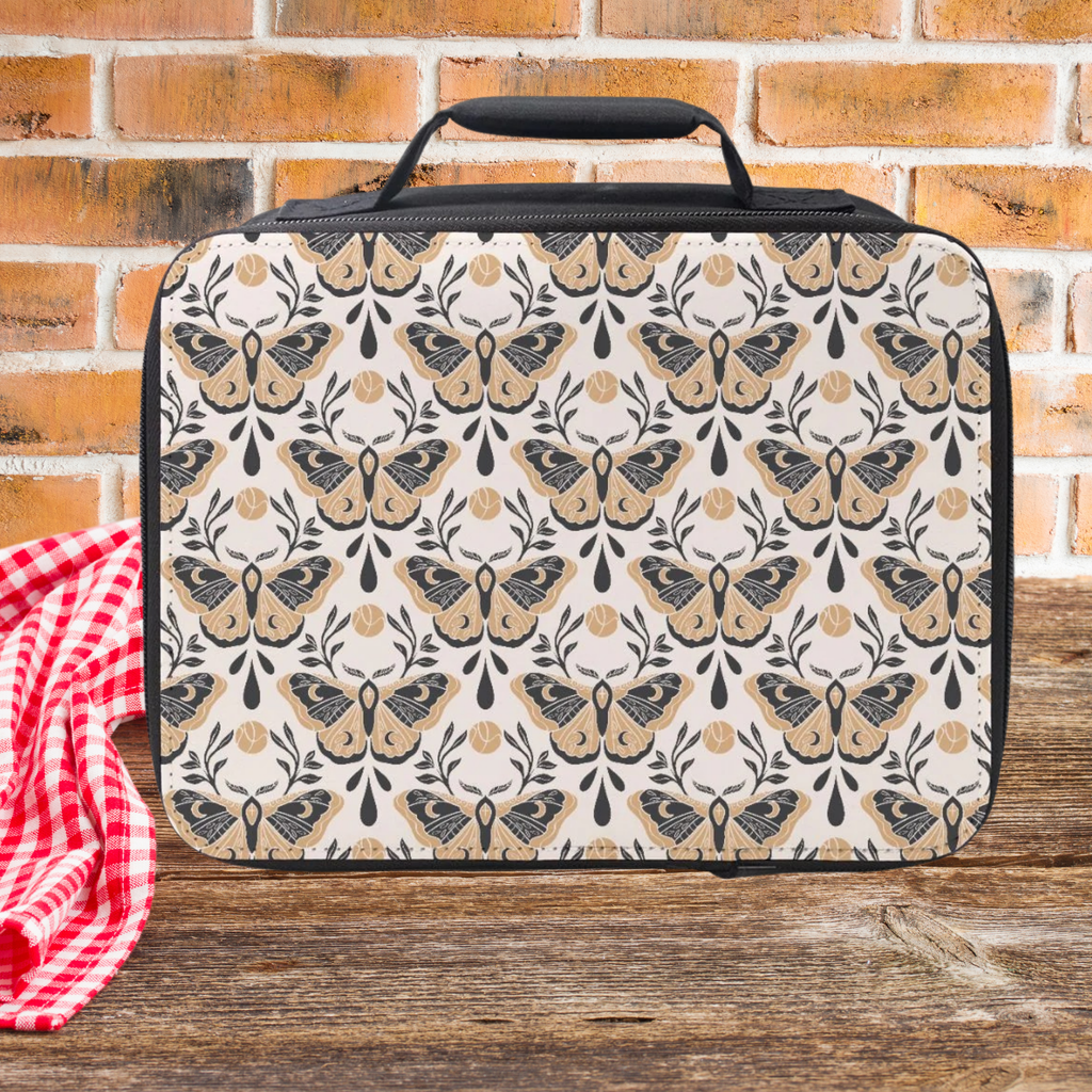 Patterned lunch bag with moth design on a wooden picnic table and brick wall background