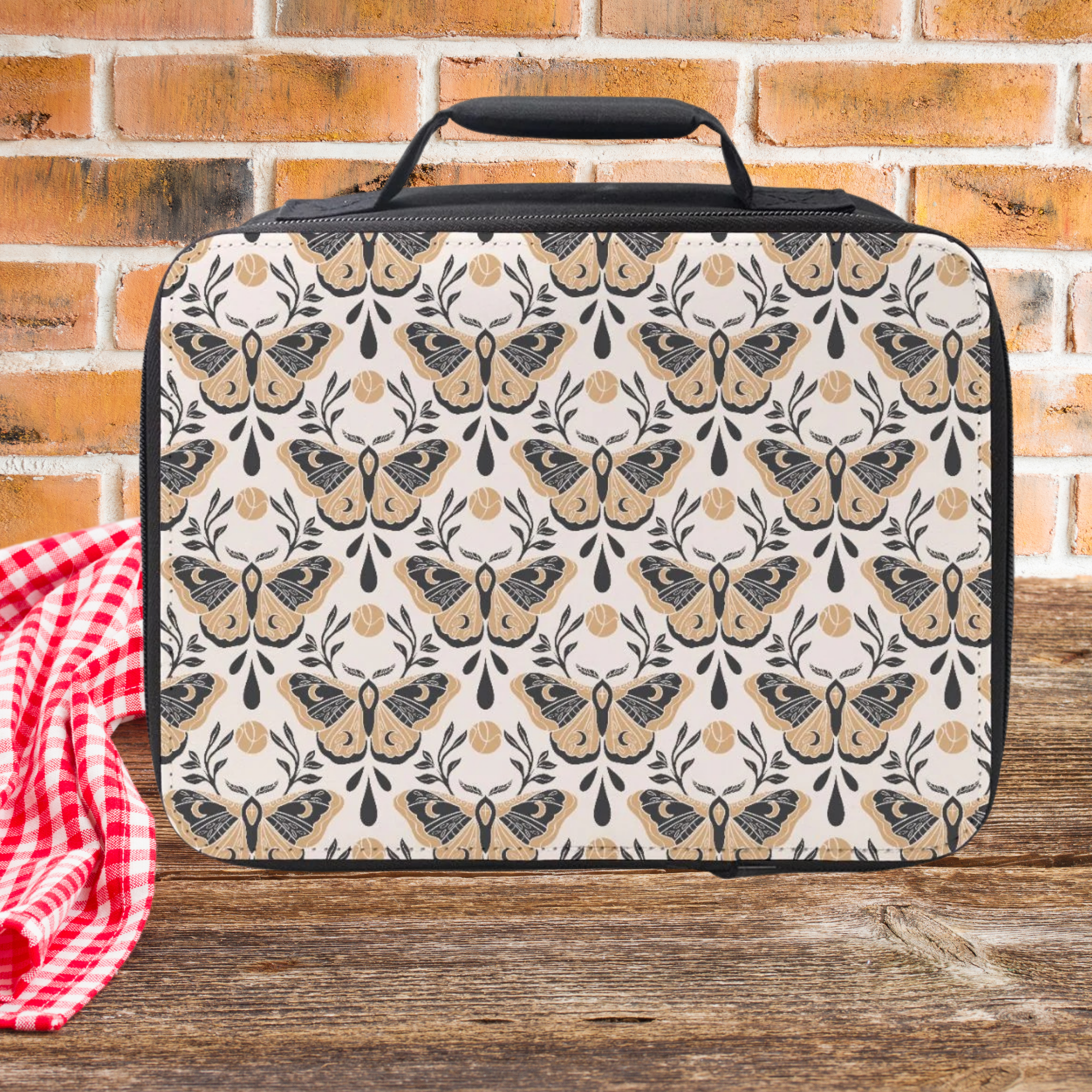 Patterned lunch bag with moth design on a wooden picnic table and brick wall background
