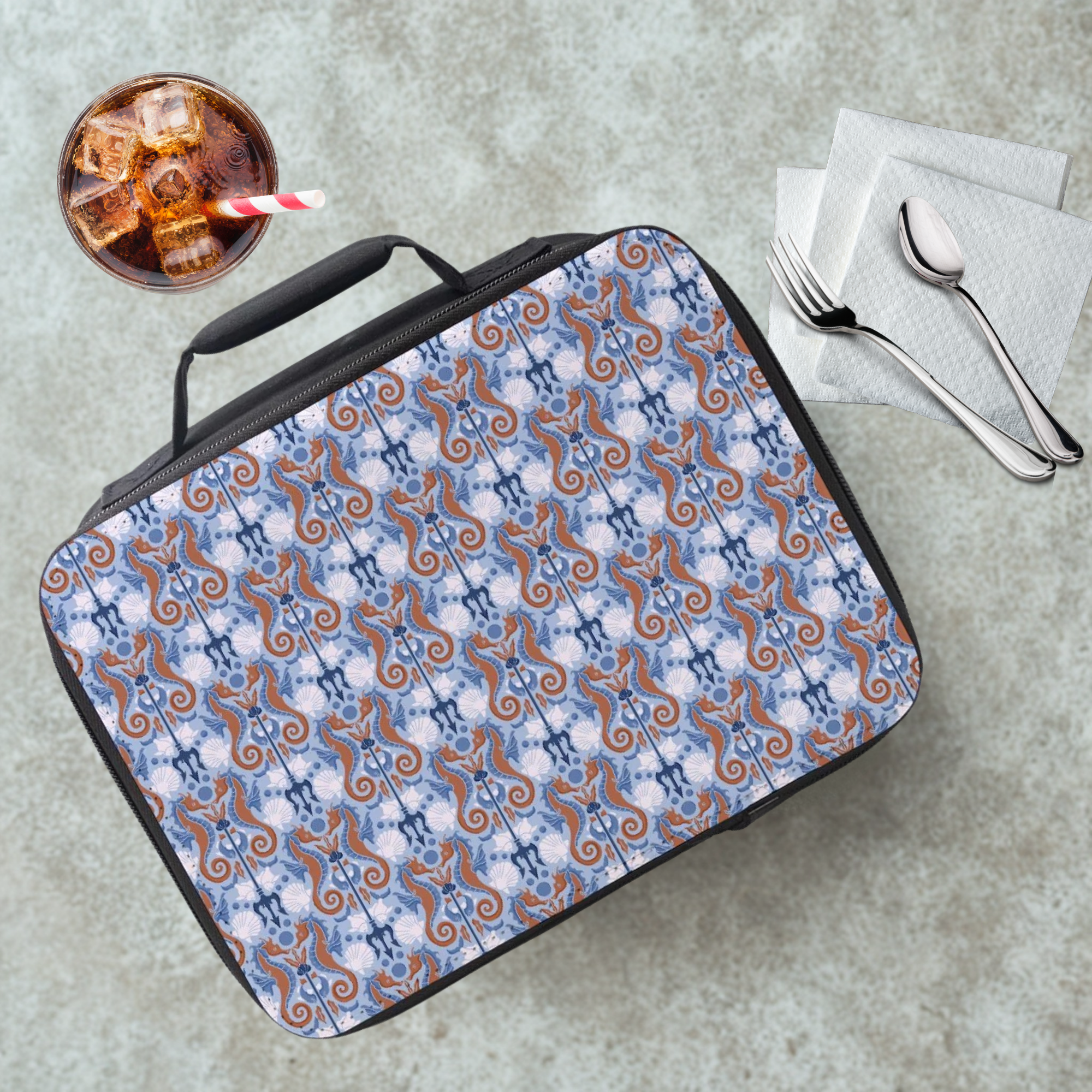 Seahorse patterned lunch bag on a cafeteria table with a drink and utensils.