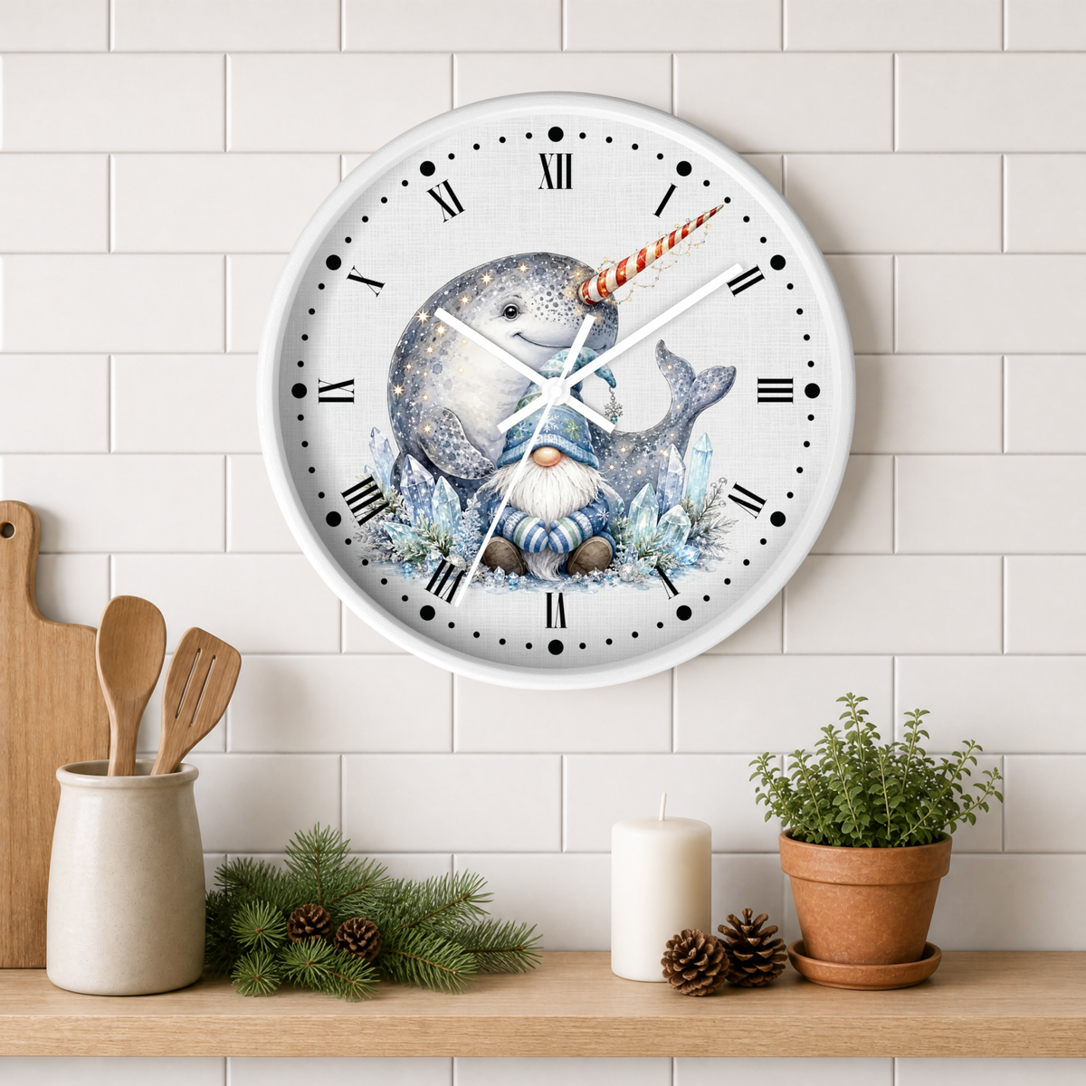 A round wall clock with a whimsical illustration of a narwhal and a gnome on the face, mounted on a white subway tile wall above a wooden shelf with kitchen props.