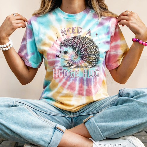 Person wearing a tie-dye t-shirt with a hedgehog graphic and text 'NEED A HEDGE HUG'.
