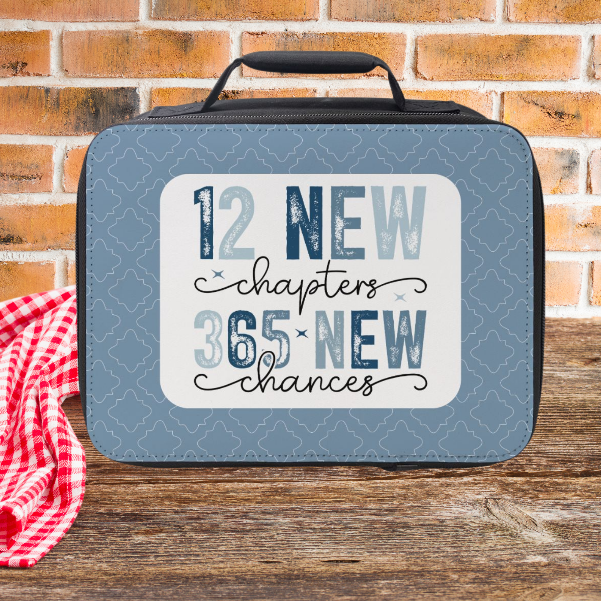 Blue lunch bag with motivational quote on a wooden picnic table and brick wall background