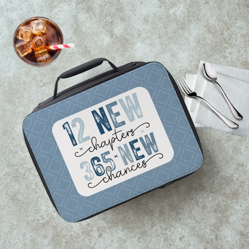 Lunch box with motivational quote on a cafeteria table with a drink and utensils.