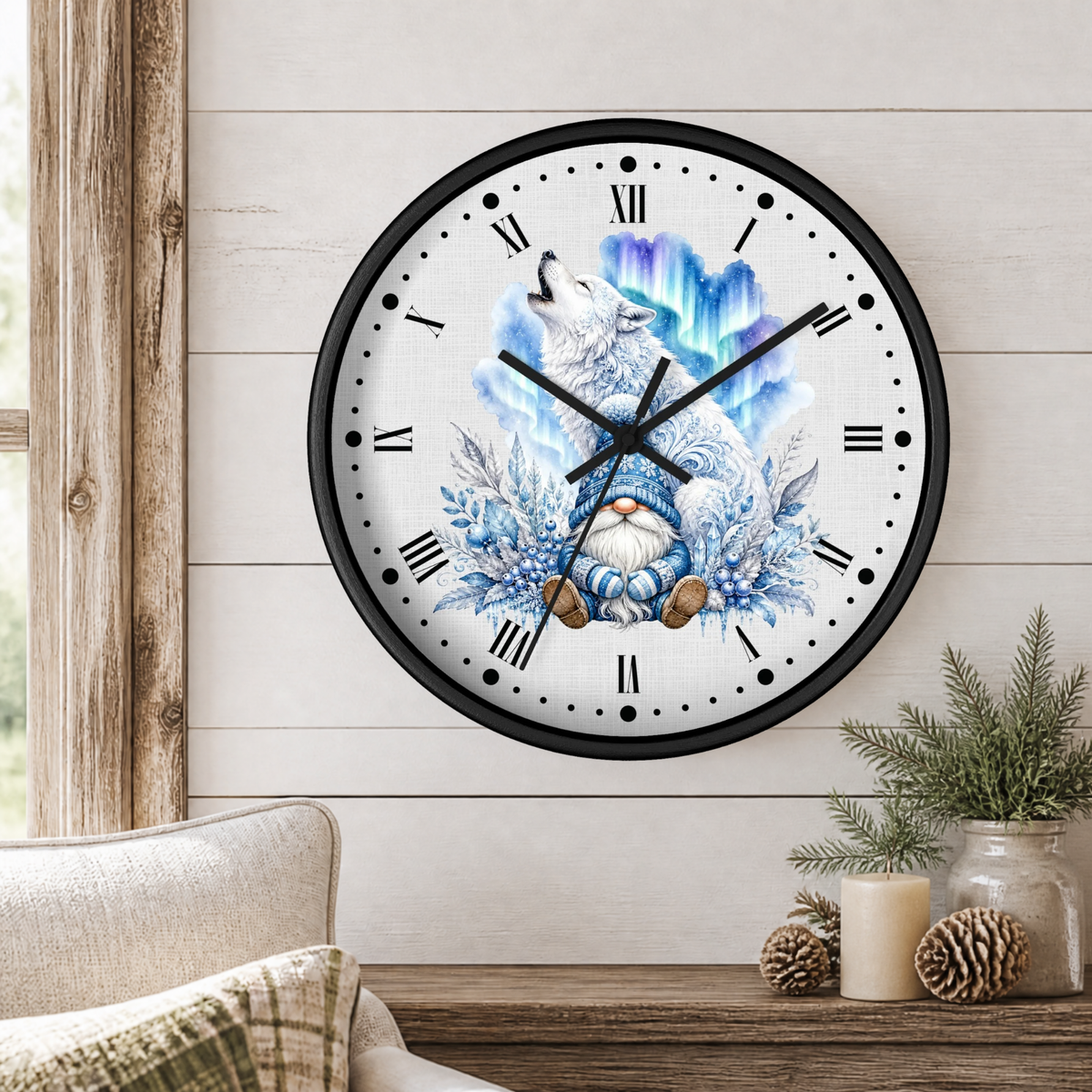 A round wall clock with a black frame and a whimsical winter illustration of a gnome under a howling wolf and aurora design, mounted on a white wood-paneled wall above a rustic table with pinecones and a candle.
