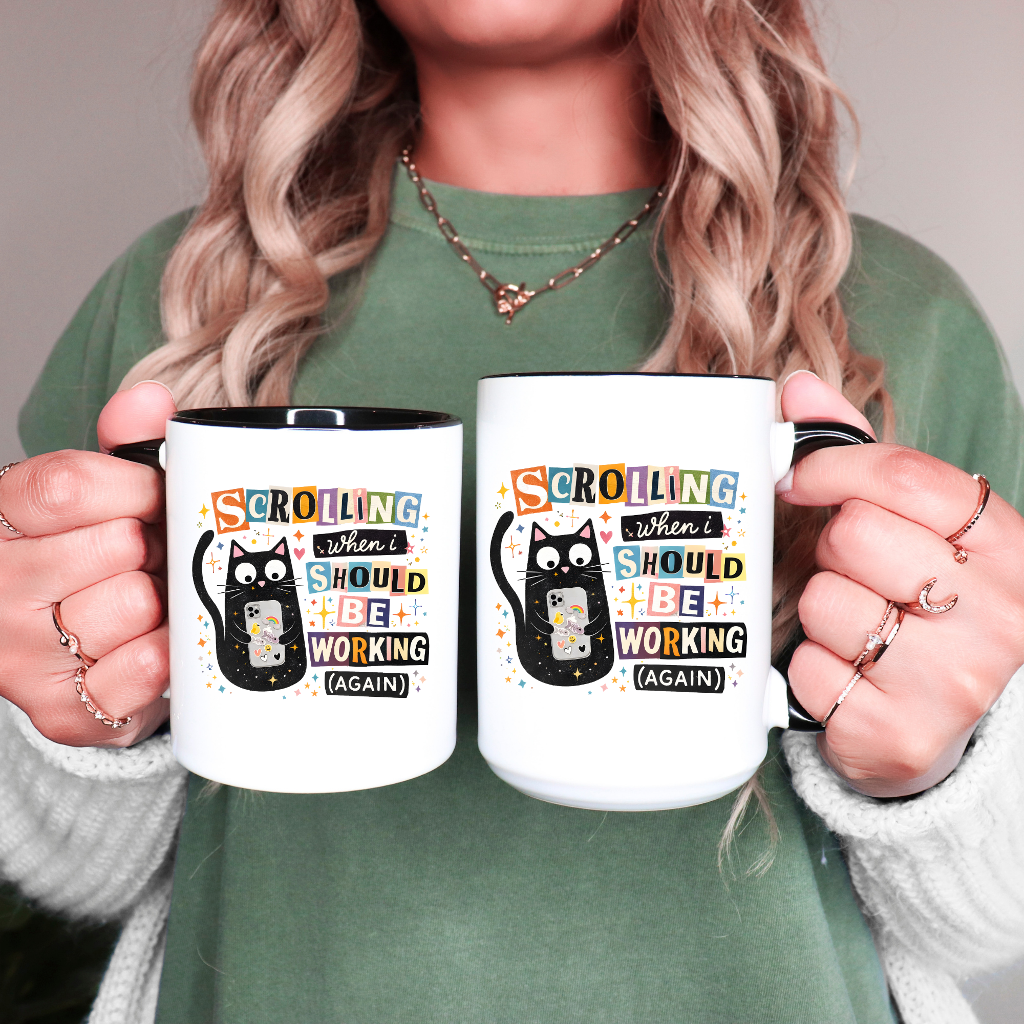 Person holding two mugs with a humorous cat design and text.