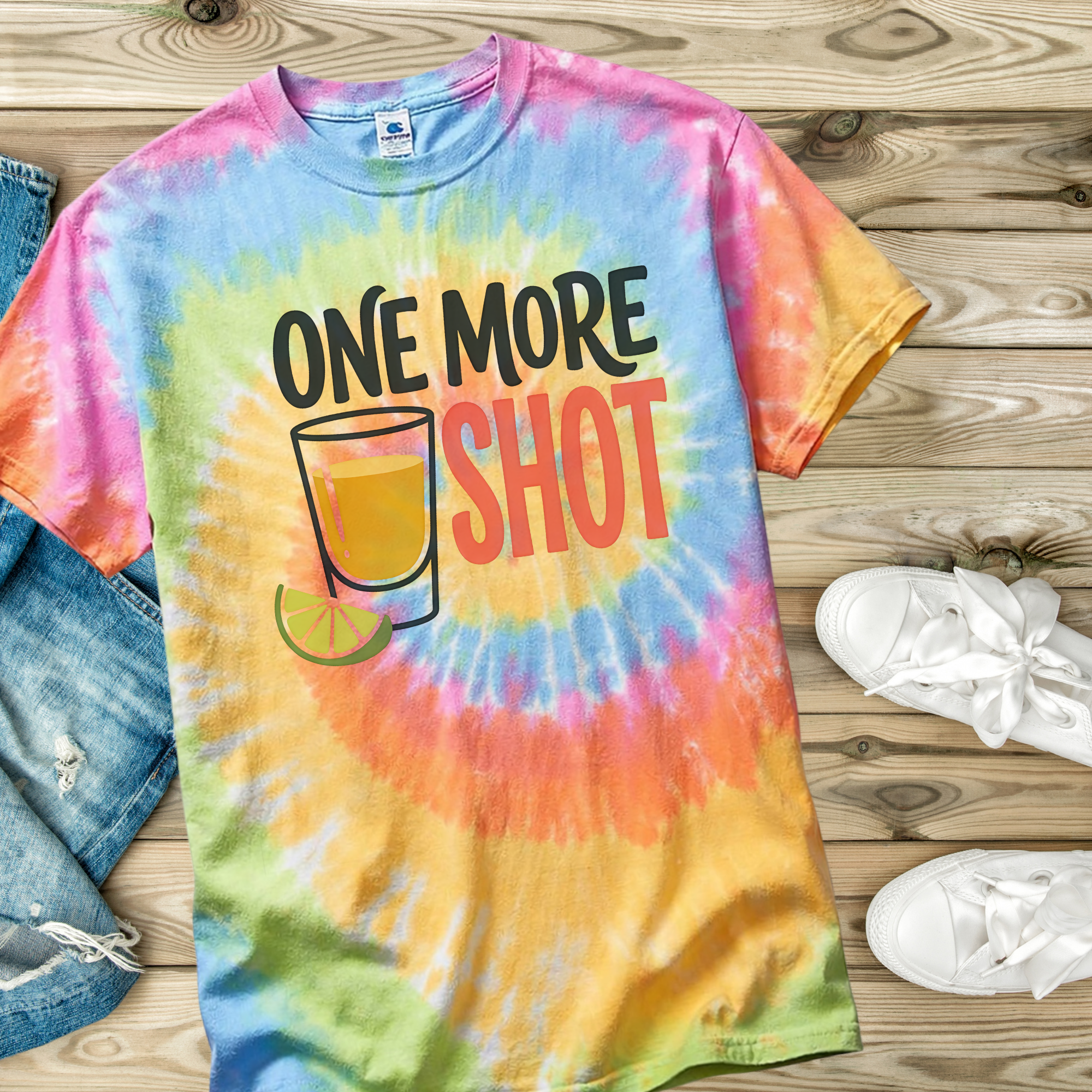 Tie-dye t-shirt in the color Eternity with 'One More Shot' graphic on a wooden surface with jeans and shoes.