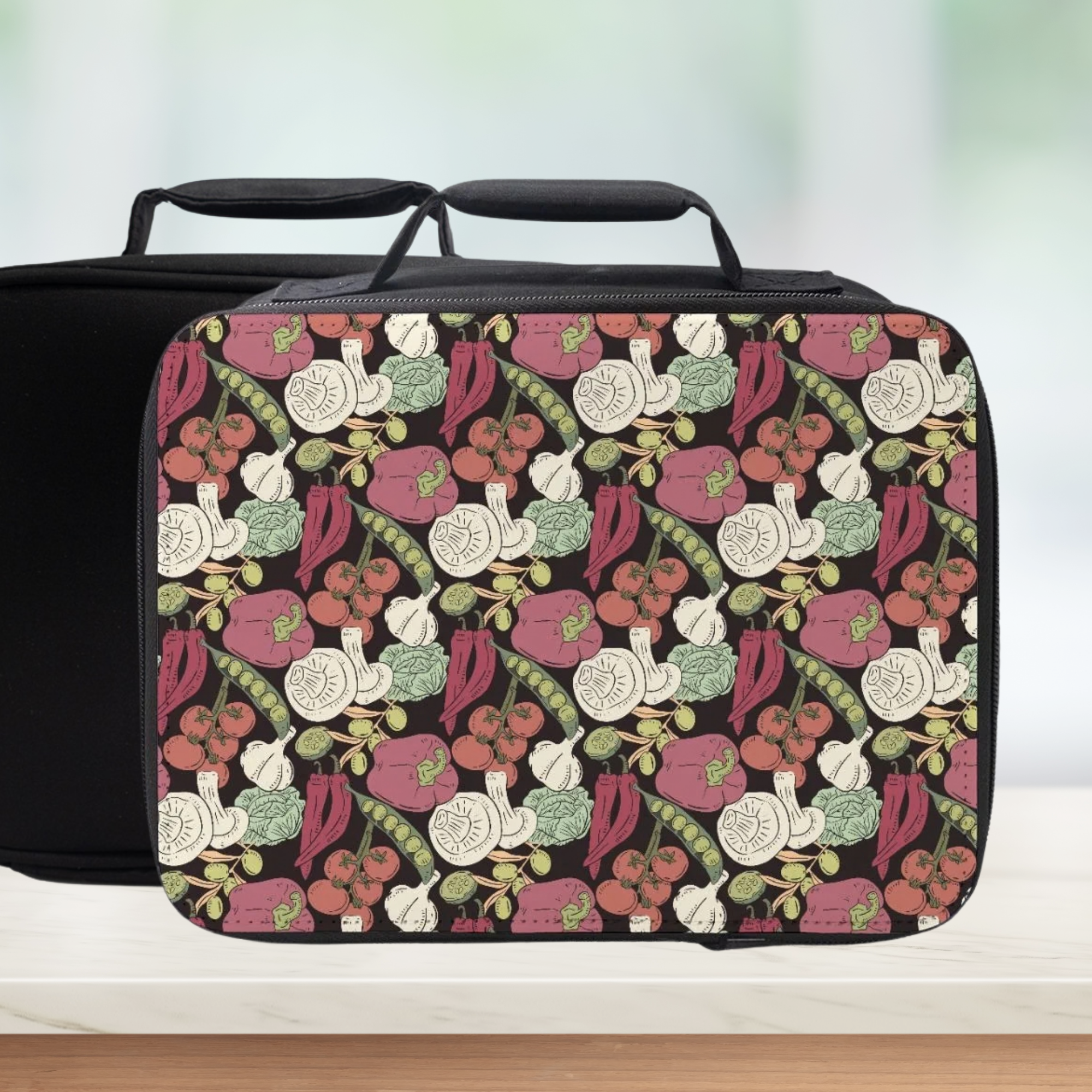 Insulated black lunch bag with colorful vegetable pattern on a white surface.