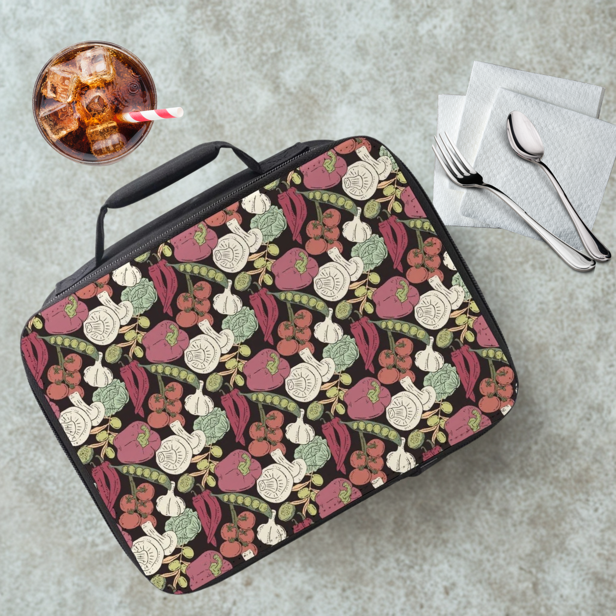 insulated lunch bag with vegetable pattern on a cafeteria table with a drink and utensils.