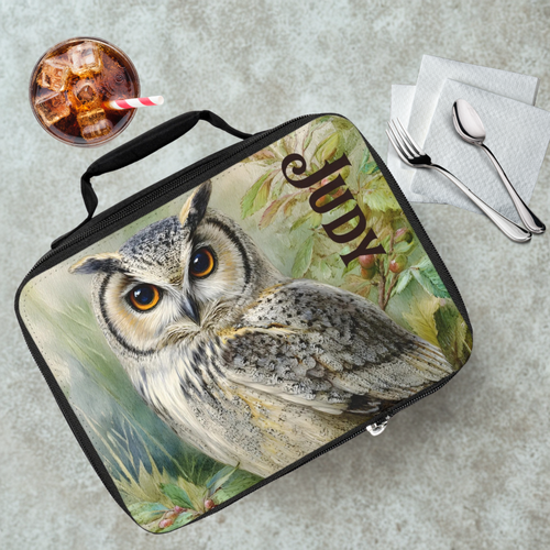 Lunch bag with owl design and 'Judy' text on a cafeteria table with a drink and utensils.