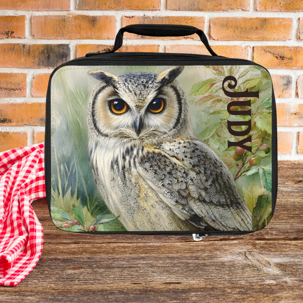  insulated lunch bag with an owl design and the name 'Judy' on a picnic table against a  brick wall background