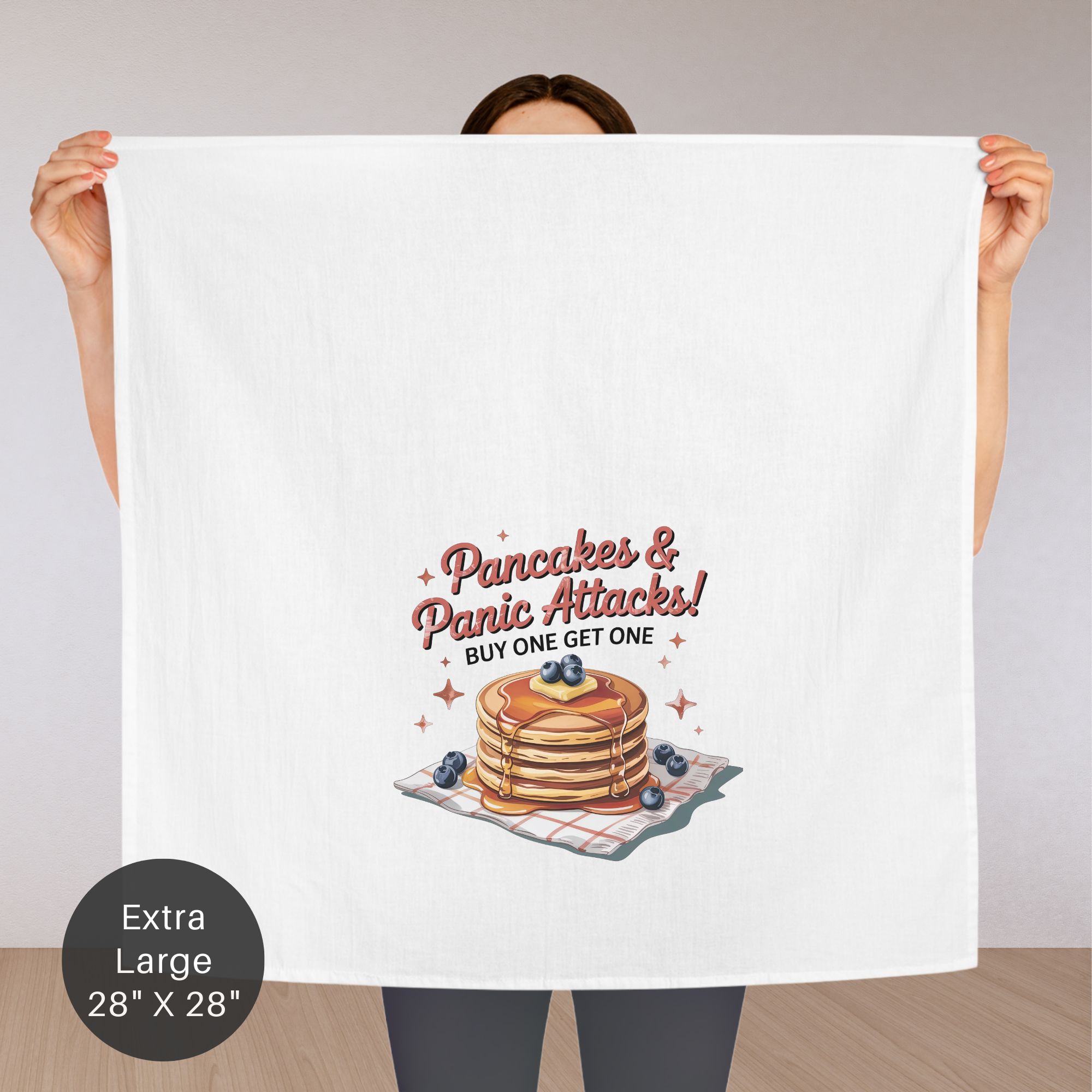 Person holding an extra large tea towel with a stack of pancakes and text design.