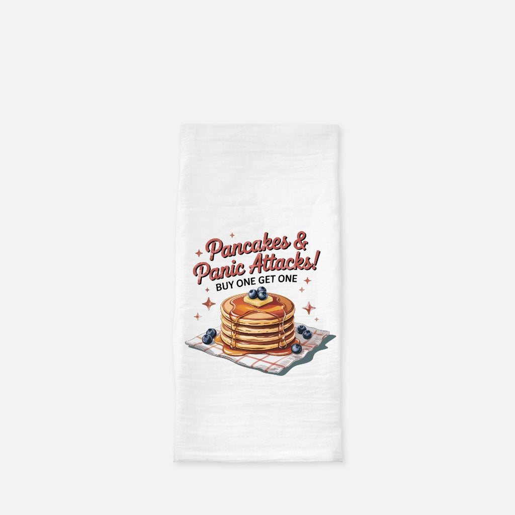 Tea towel with a design of pancakes and text 'Pancakes & Panic Attacks! Buy One Get One' on a white background.