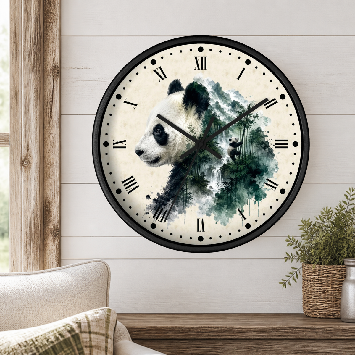 A round wall clock with a black frame and a panda illustration over a green watercolor forest design, mounted on a white wood-paneled wall above a wooden shelf with a plant and part of a sofa visible.